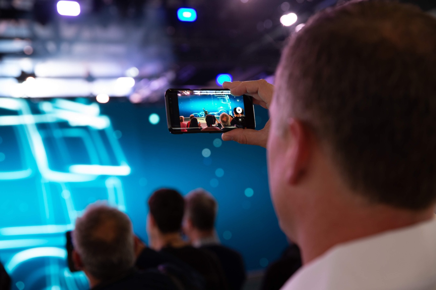Ein Besucher der IAA filmt die Bühnenshow mit seinem Smartphone