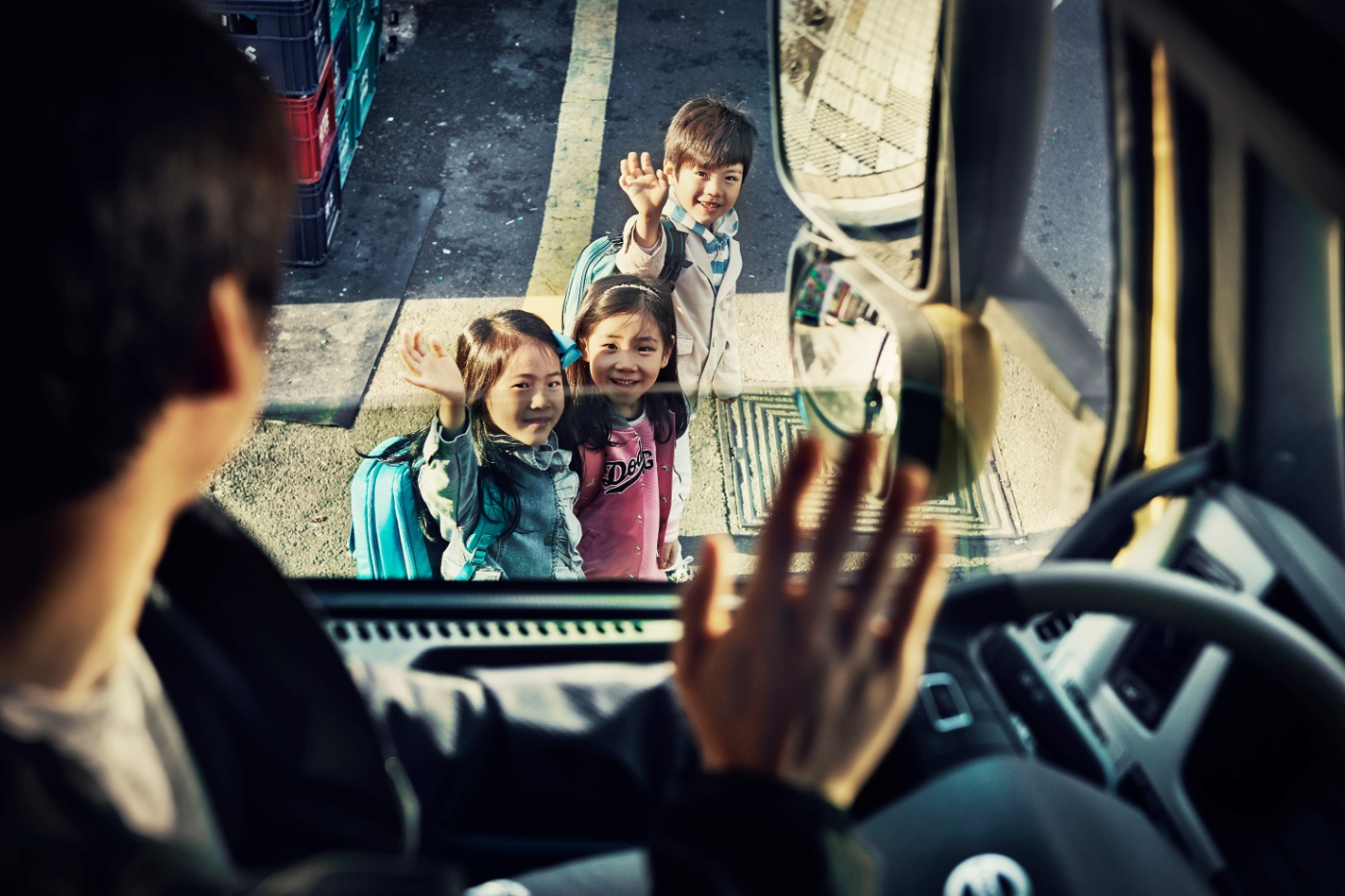 Kinder winken einem Lkw-Fahrer im Fahrerhaus zu