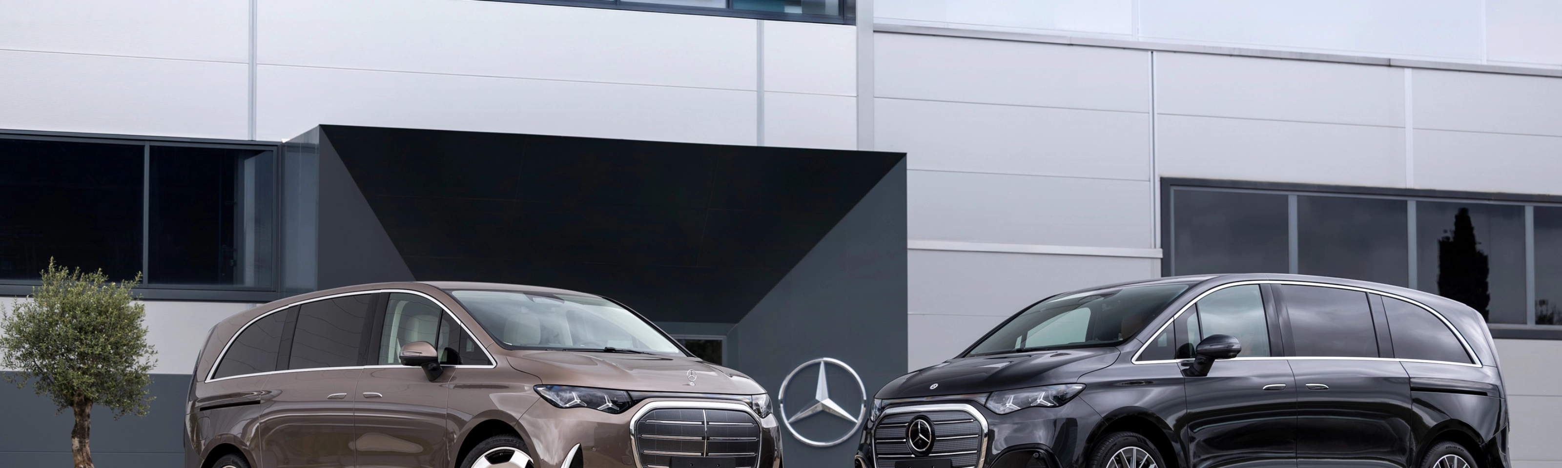 Zwei Mercedes-Benz Vans vor einem modernen Bürogebäude.