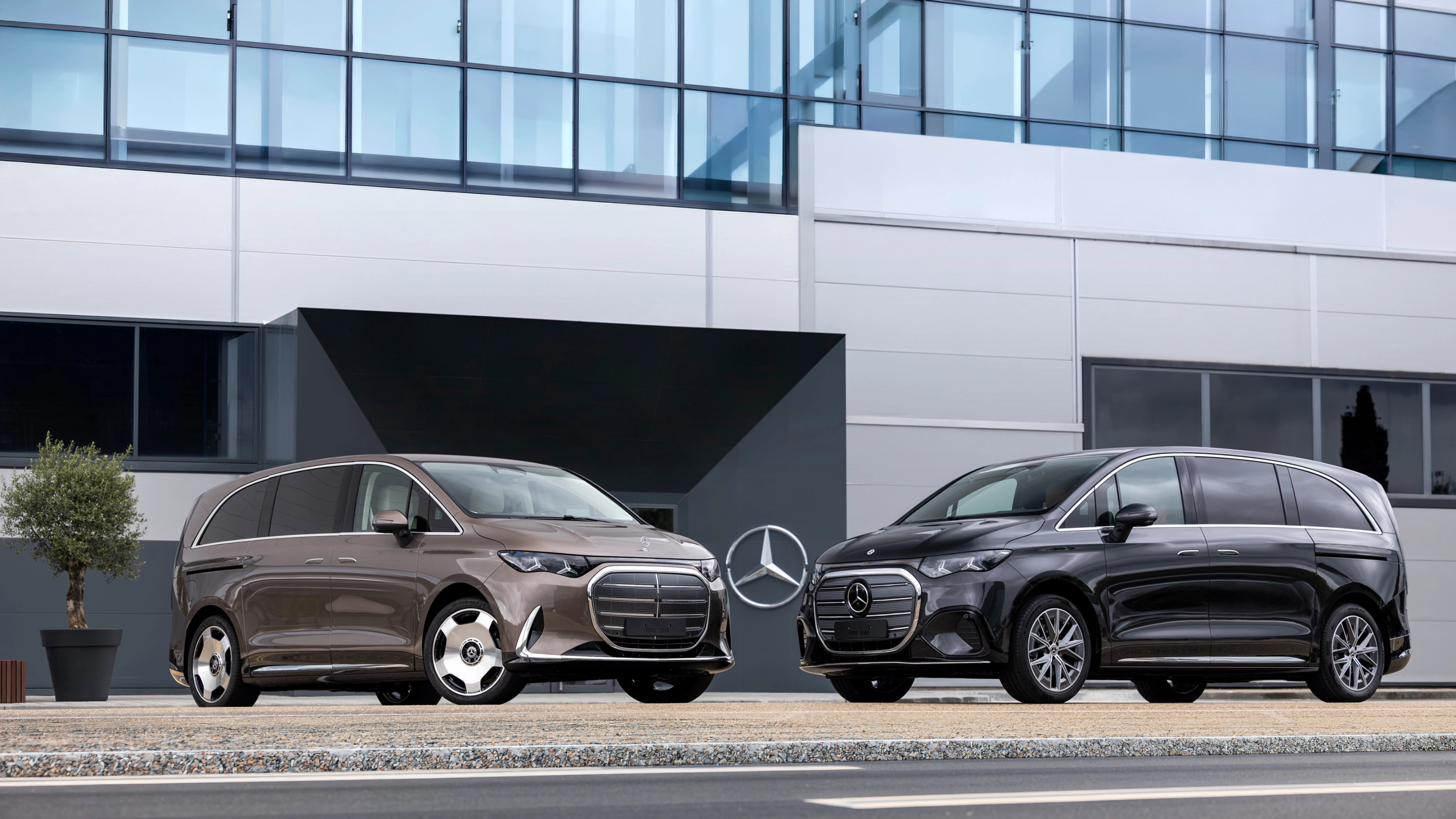 Zwei Mercedes-Benz Vans vor einem modernen Bürogebäude.