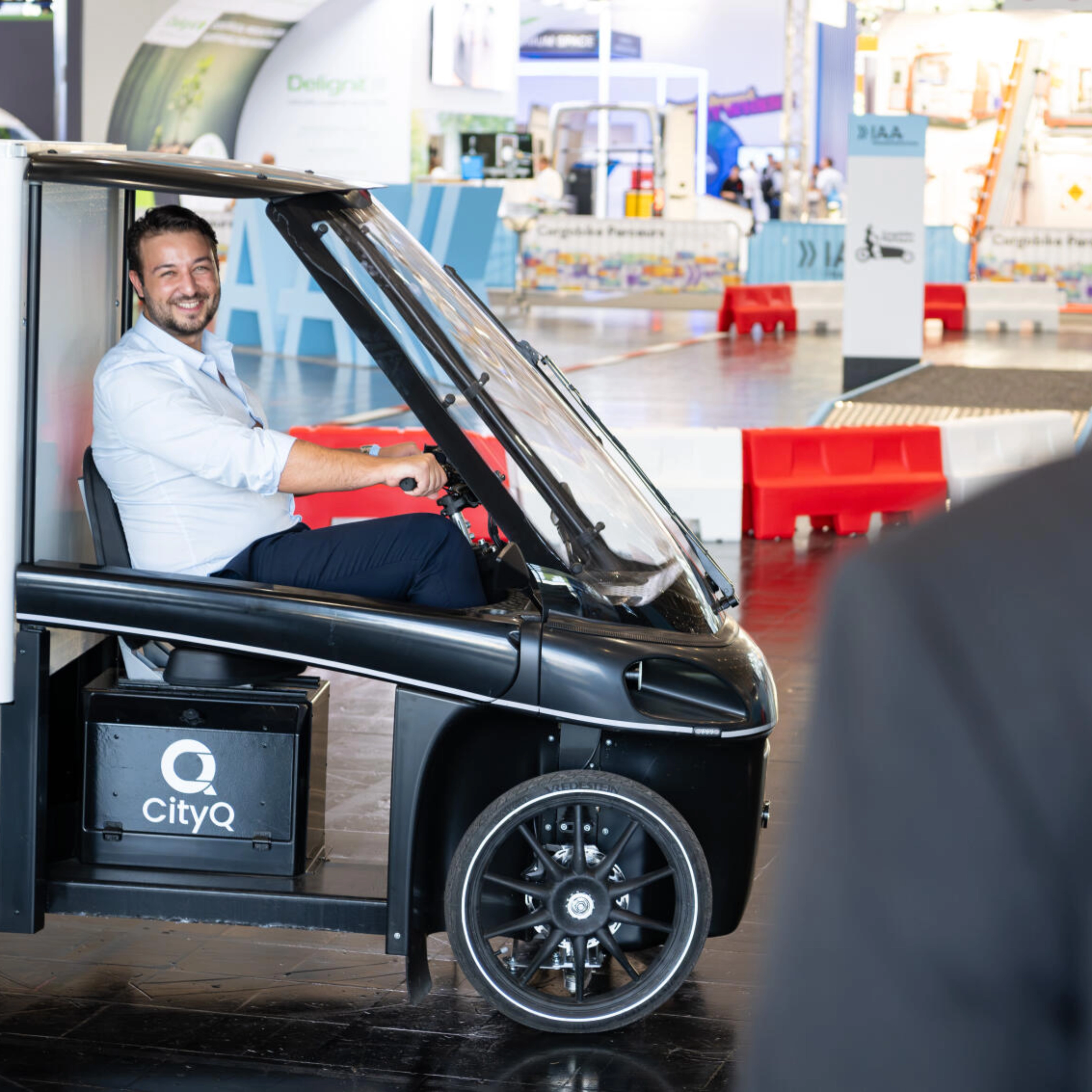 Mann sitzt in einem CityQ Lastenrad in einer Messehalle.