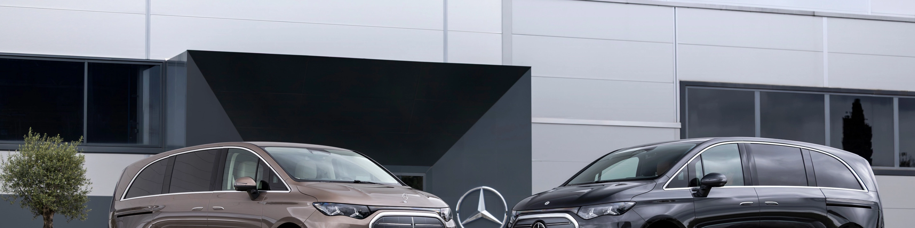 Zwei Mercedes-Benz Vans vor einem modernen Bürogebäude.