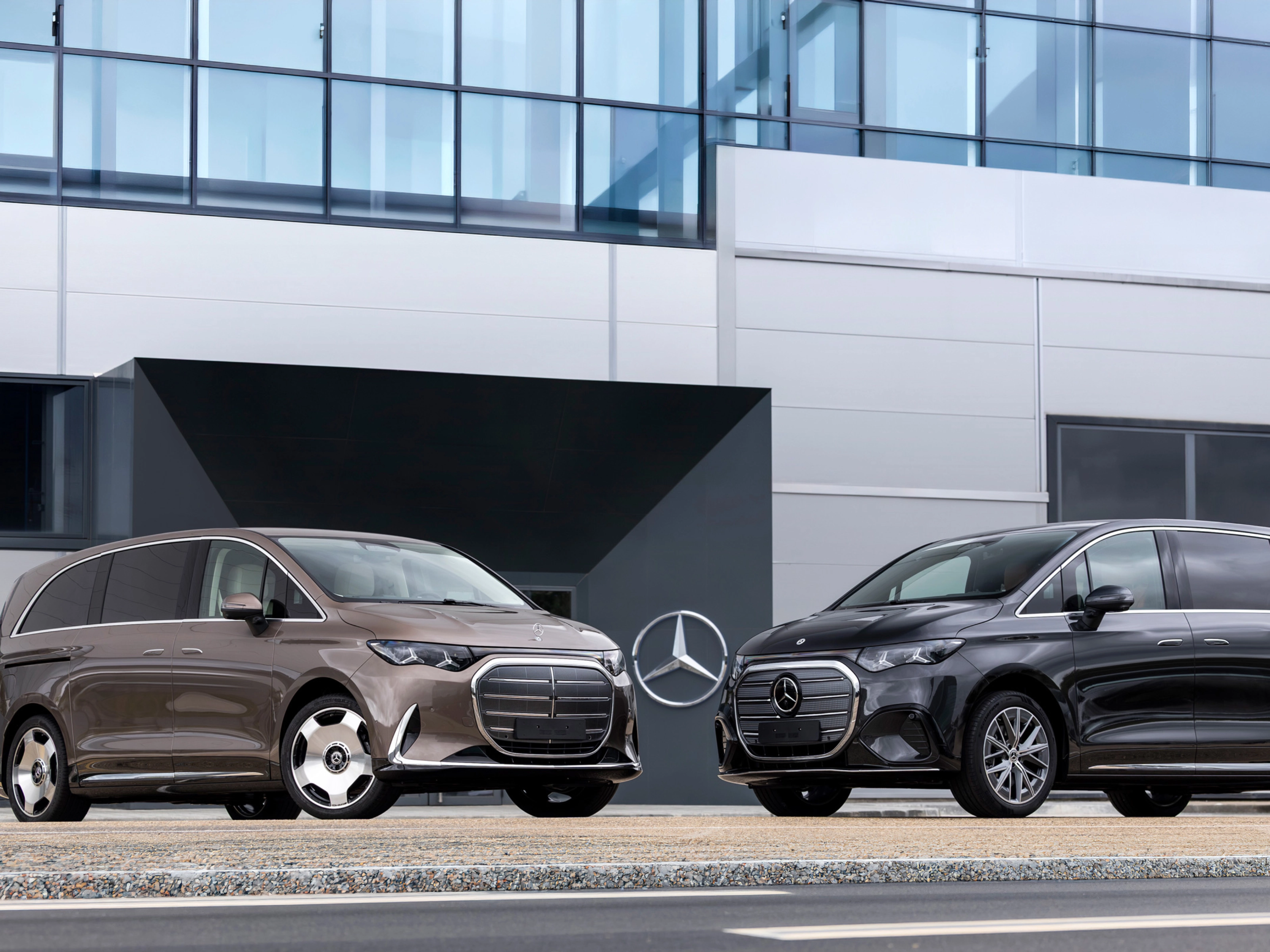 Zwei Mercedes-Benz Vans vor einem modernen Bürogebäude.
