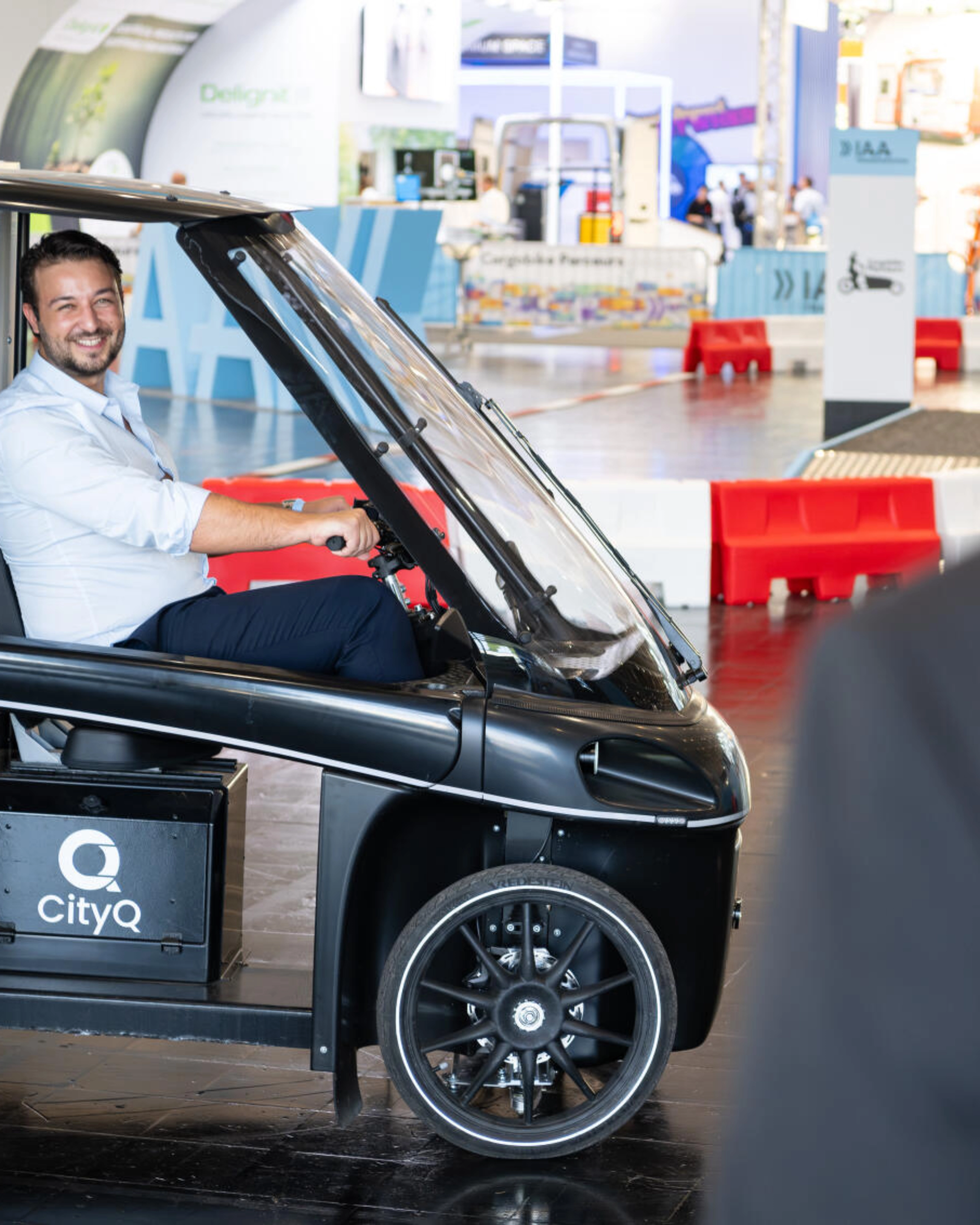 Mann sitzt in einem CityQ Lastenrad in einer Messehalle.