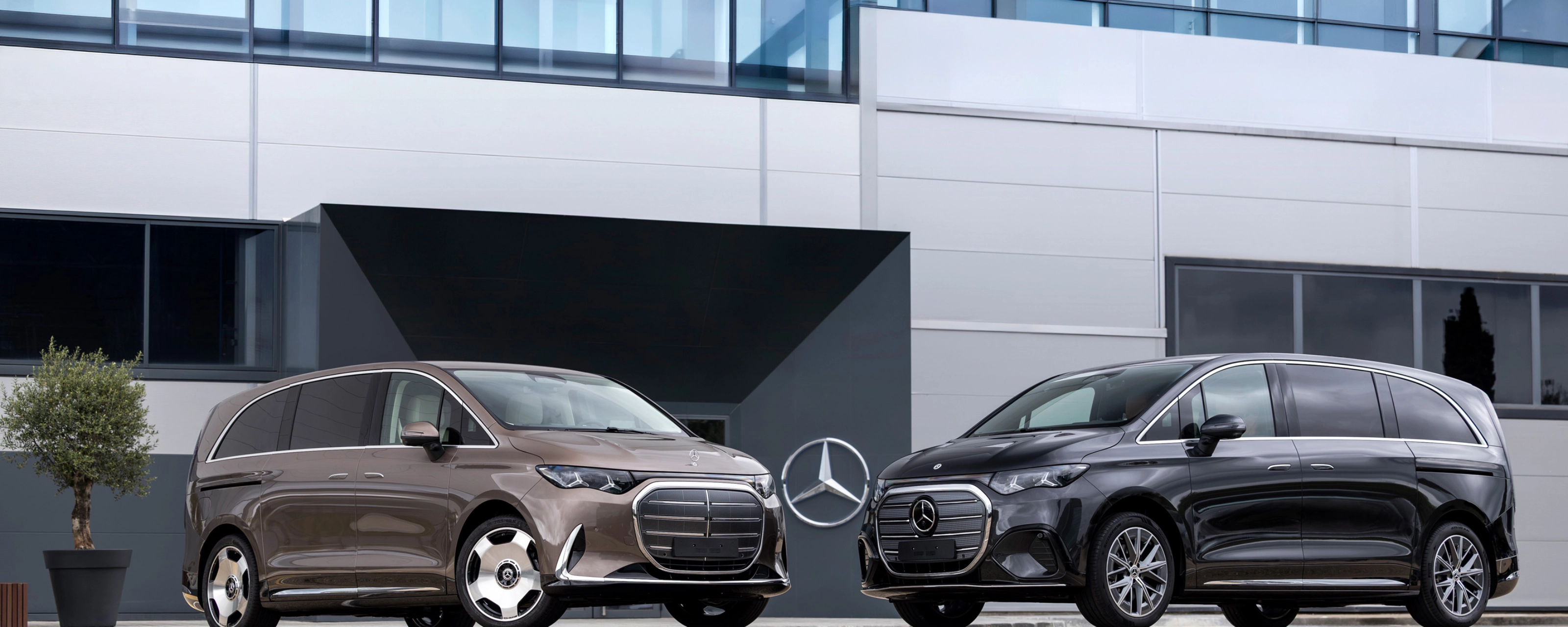 Zwei Mercedes-Benz Vans vor einem modernen Bürogebäude.