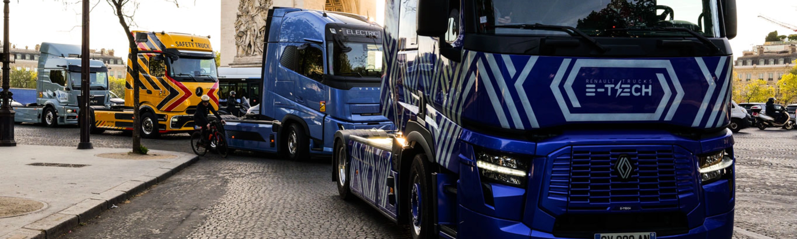 Blue electric truck driving past the Arc de Triomphe in Paris.