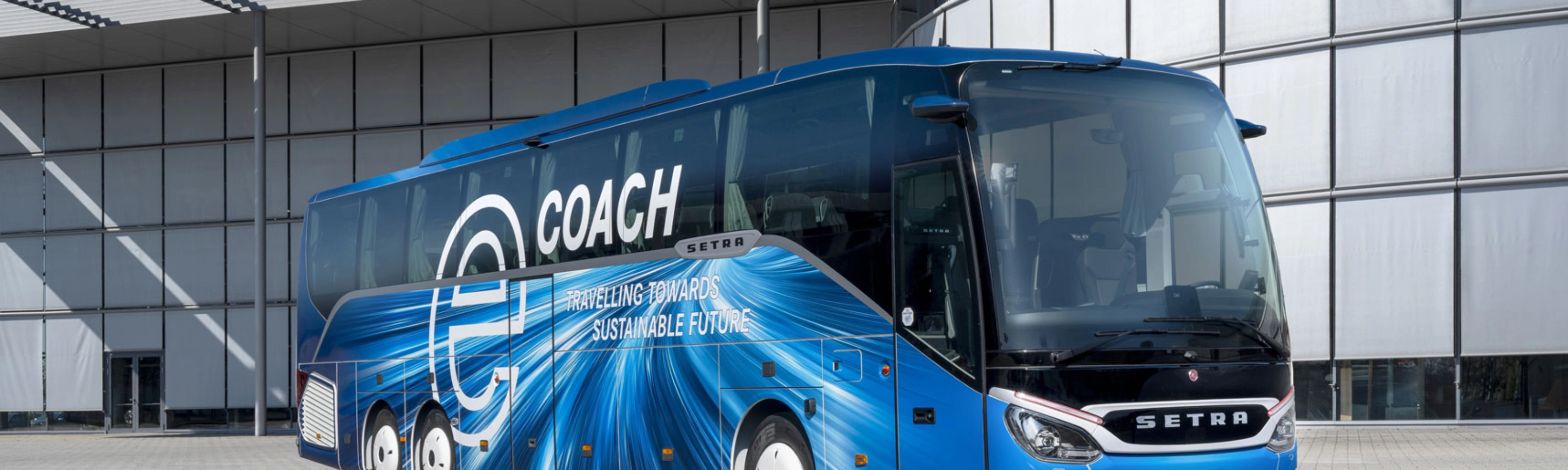 Blauer Setra-Reisebus mit Nachhaltigkeits-Slogan vor modernem Gebäude.