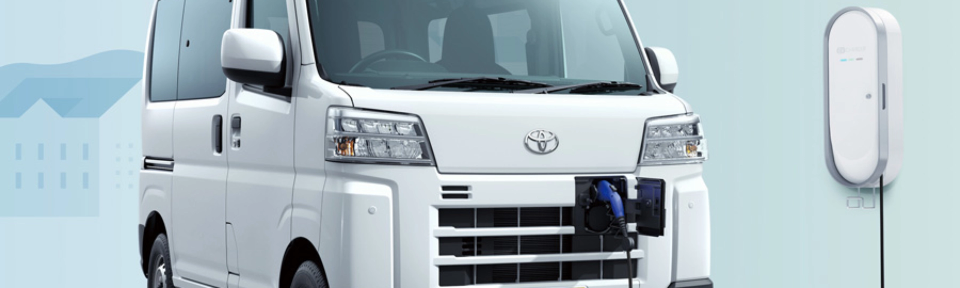 Electric van labeled "Pixis Van" is charging at a wall-mounted station via front charging port.