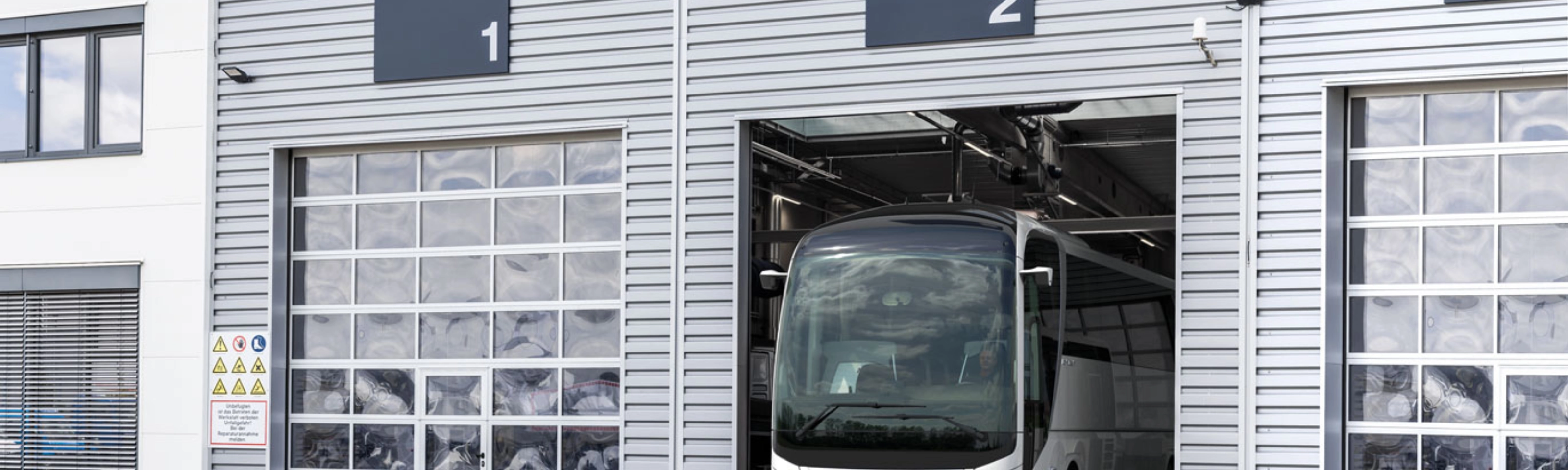 Ein Bus steht in einer nummerierten Garage eines modernen Betriebsgebäudes.