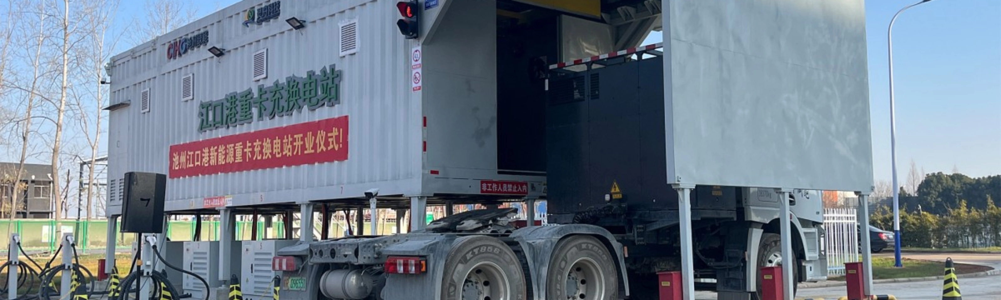 Truck at battery swap station with container module in industrial area.