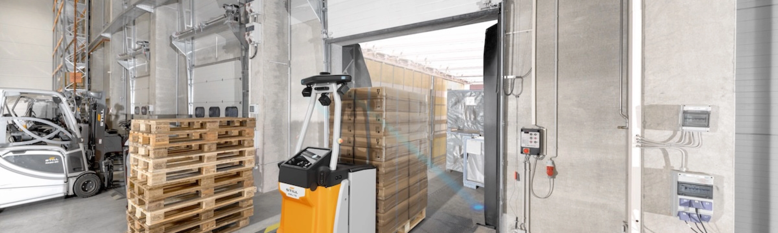 Autonomous mobile robot transporting goods at an industrial loading gate.