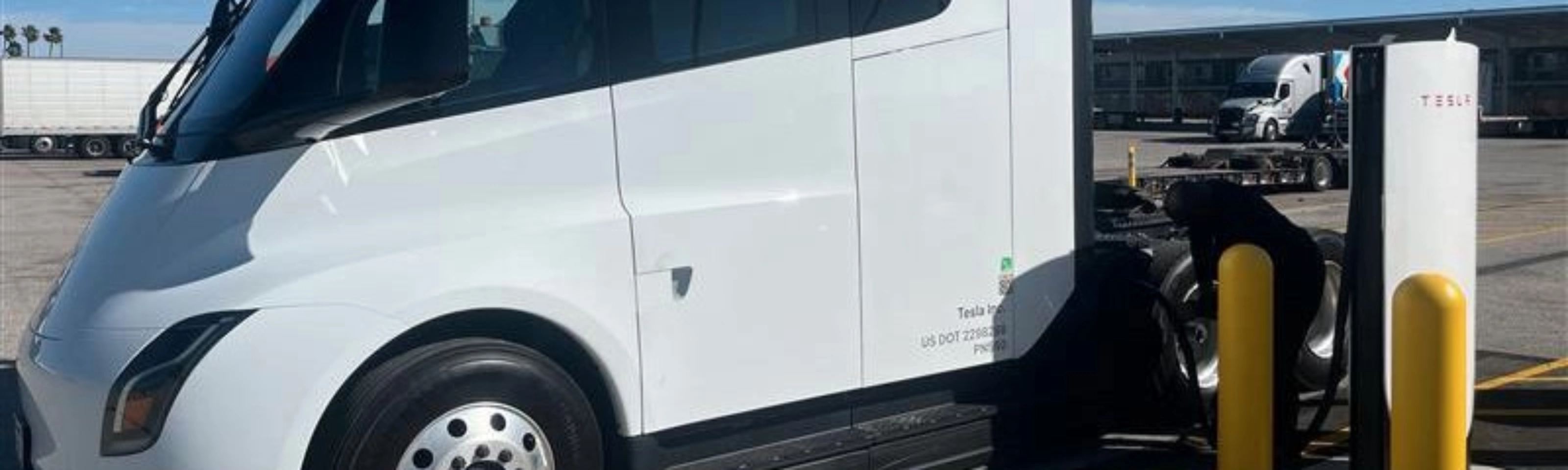 White Tesla Semi charging at a Tesla charging station.
