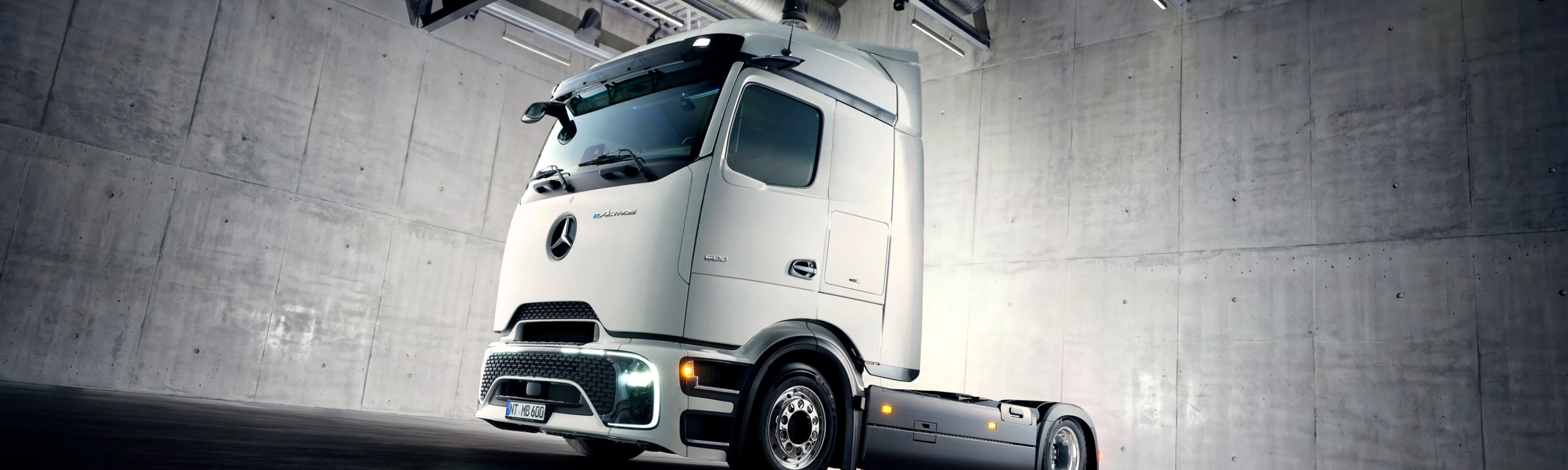 Autonomes Lkw-Fahrgestell in Industriehalle unter Scheinwerfern.