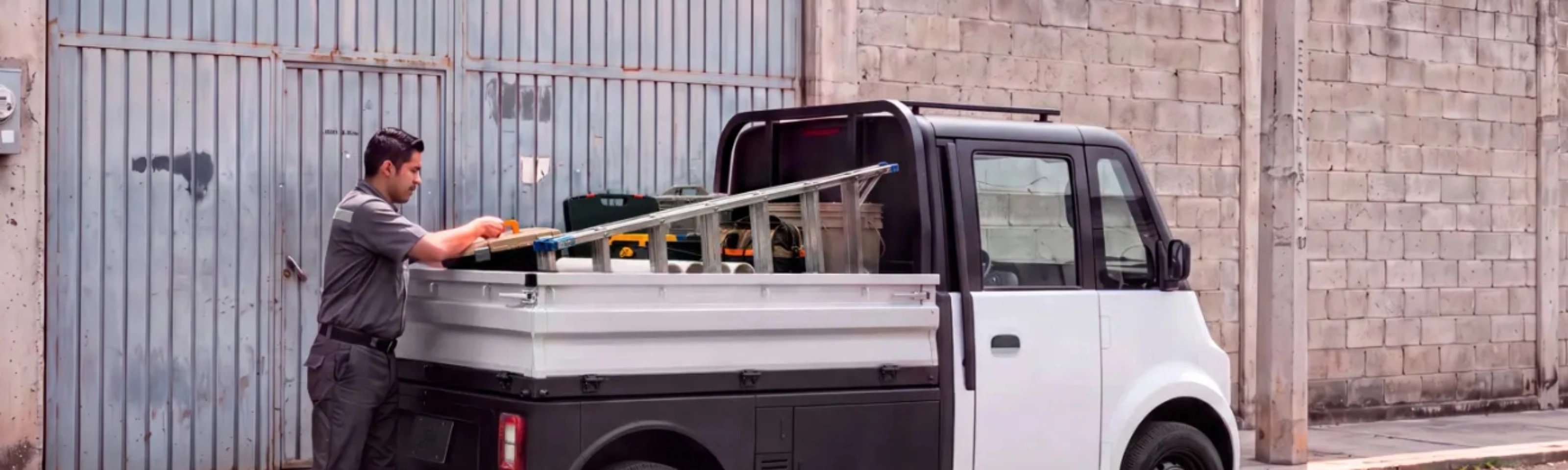 Compact Olinia utility vehicle being loaded at the roadside.