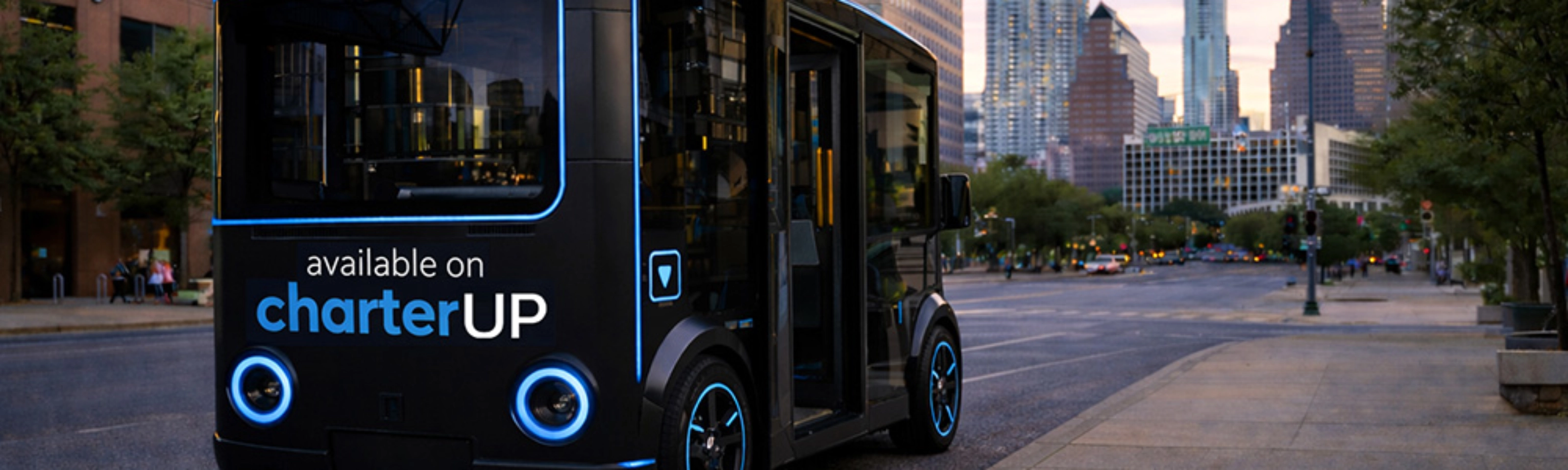 Small black electric shuttle bus with CharterUP logo in city street.