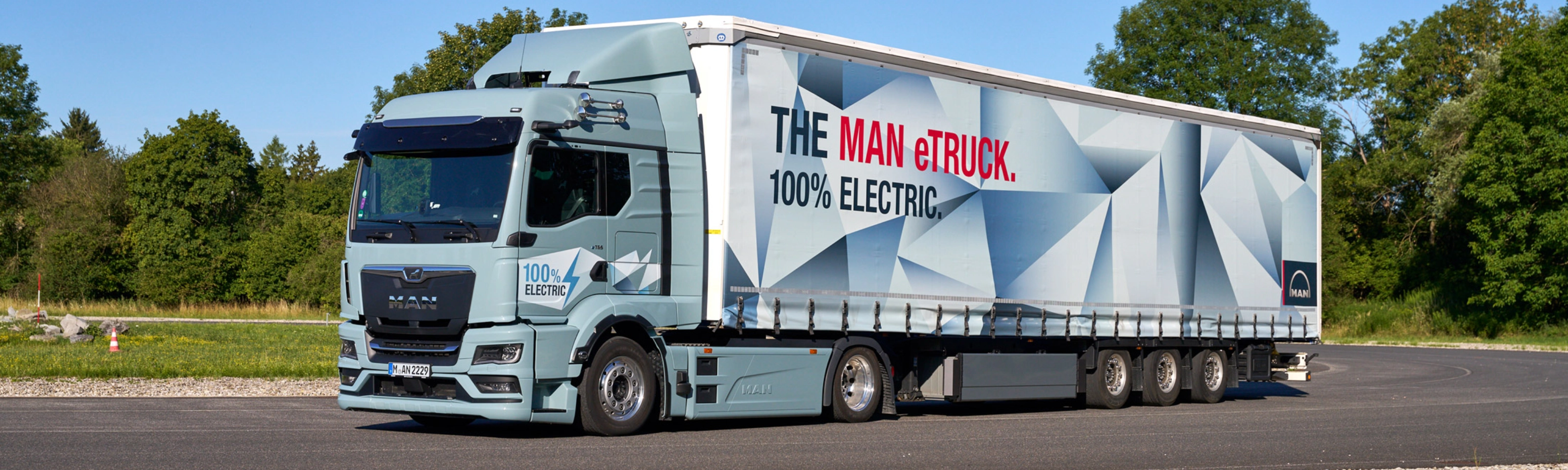 MAN truck with a trailer featuring a large graphic parked on a paved area.