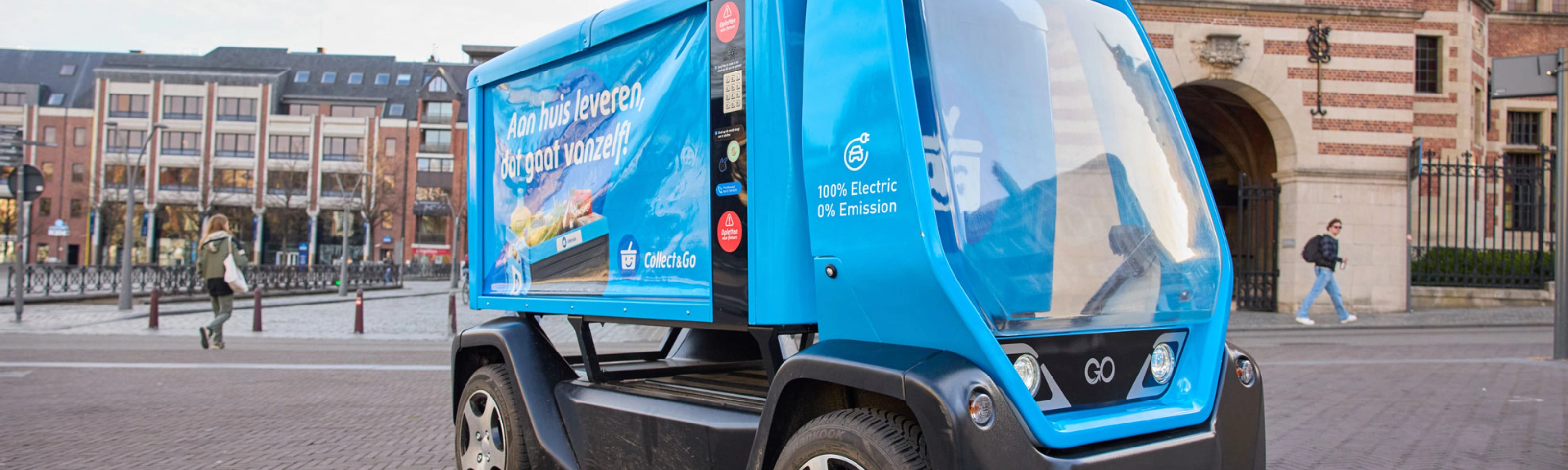 Kleines blaues Elektro-Müllfahrzeug auf einem Stadtplatz.