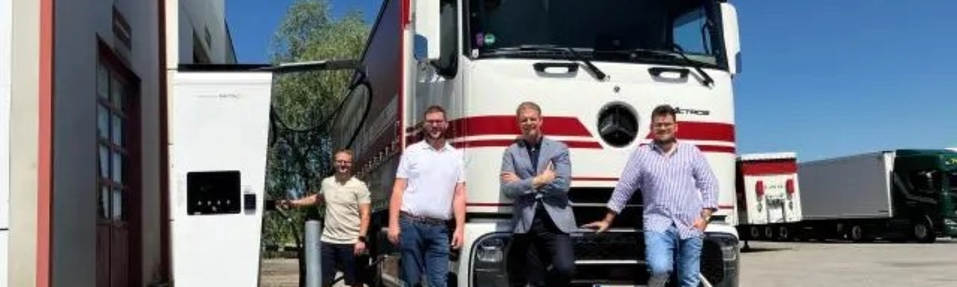 Vier Männer stehen vor einem weißen Frigel Lkw.