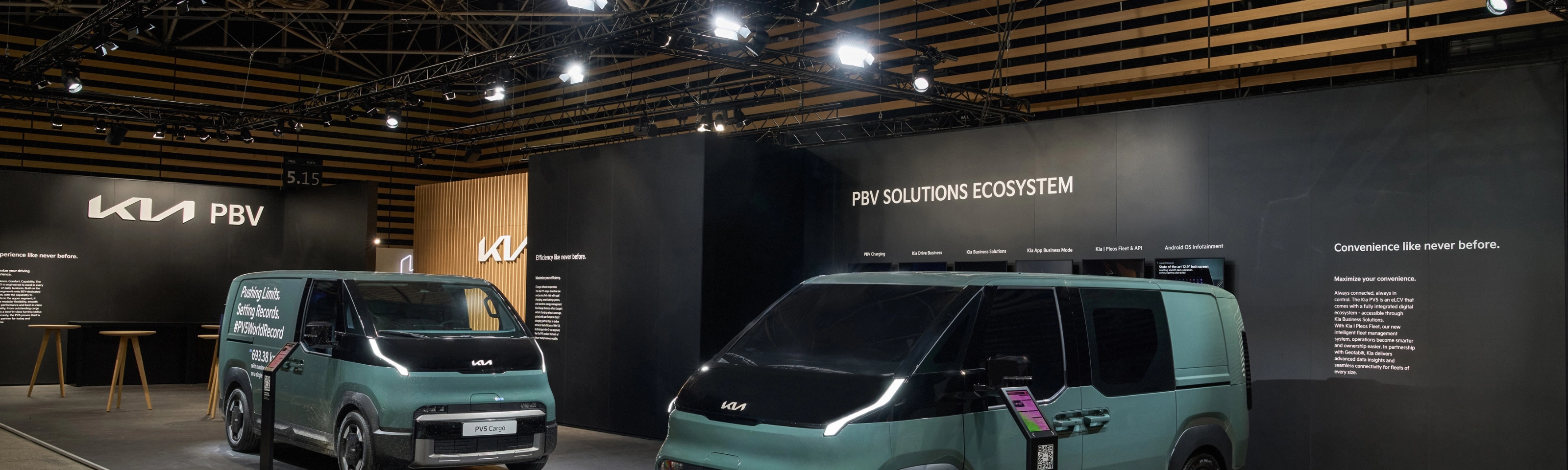 Zwei grüne Kia PBV Transporter stehen auf einem Messestand mit Kia-Logo.