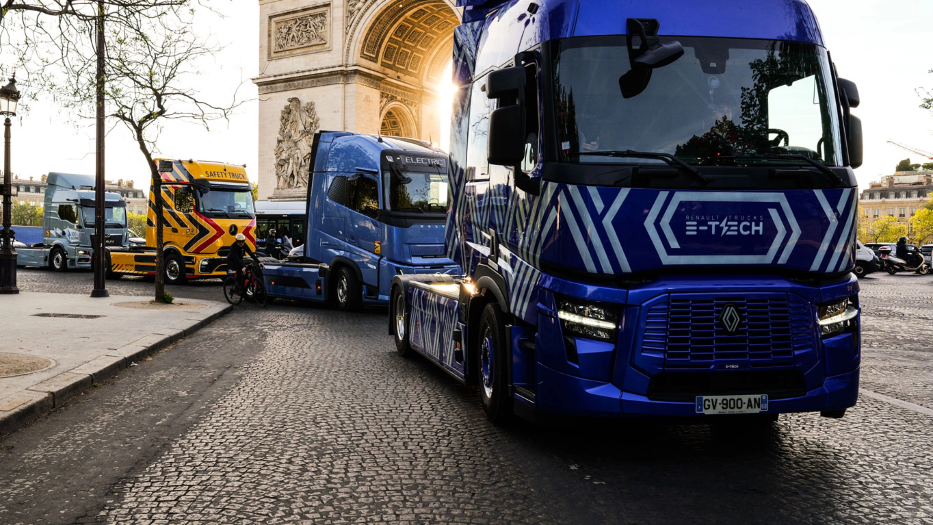 Blue electric truck driving past the Arc de Triomphe in Paris.