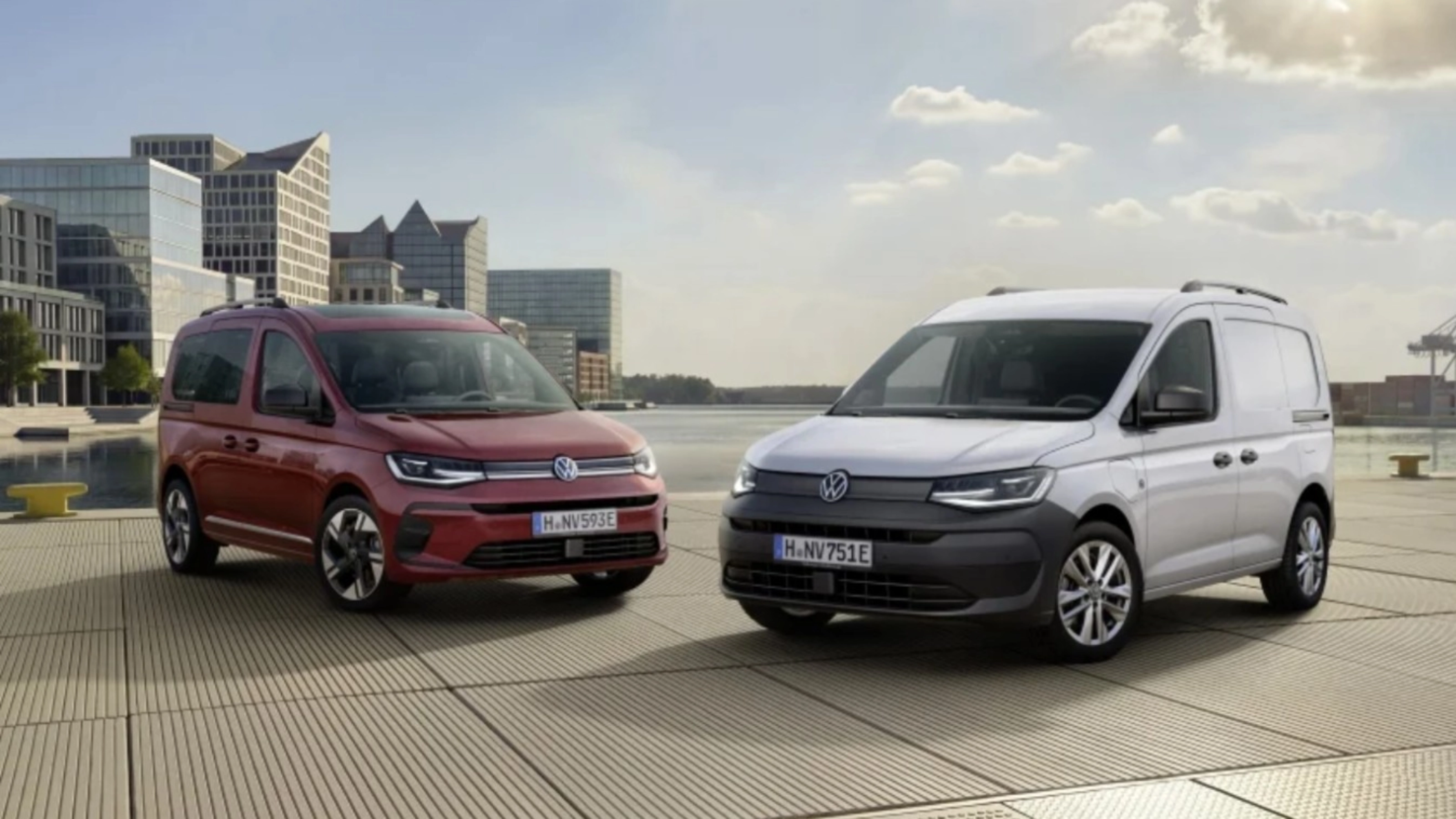 Red and white vans parked at a waterfront with modern buildings
