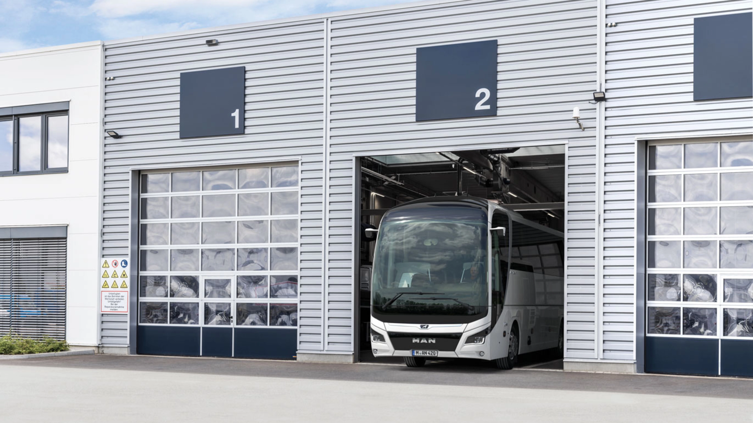 Ein Bus steht in einer nummerierten Garage eines modernen Betriebsgebäudes.
