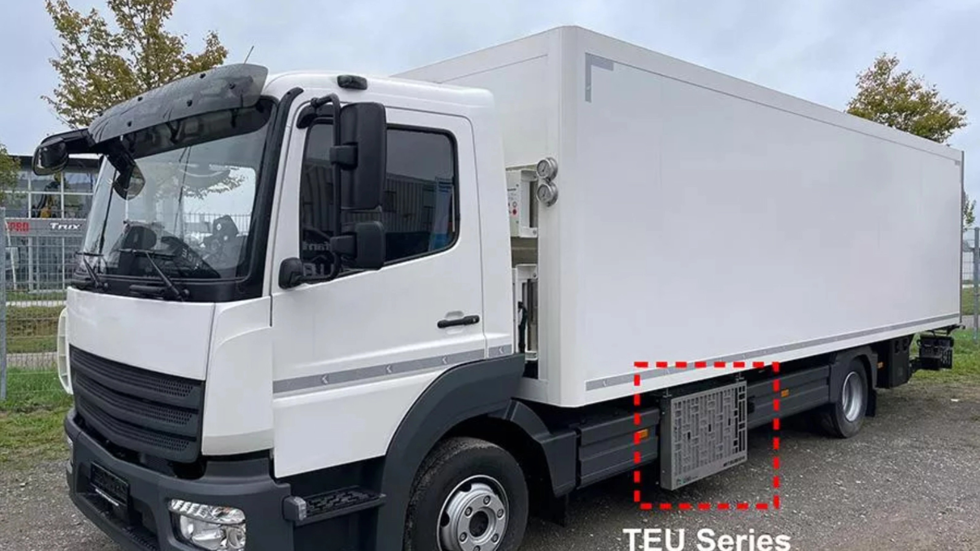 Weißer Mitsubishi Heavy Industries Koffer-Lkw mit seitlich montierten TEU-Boxen.