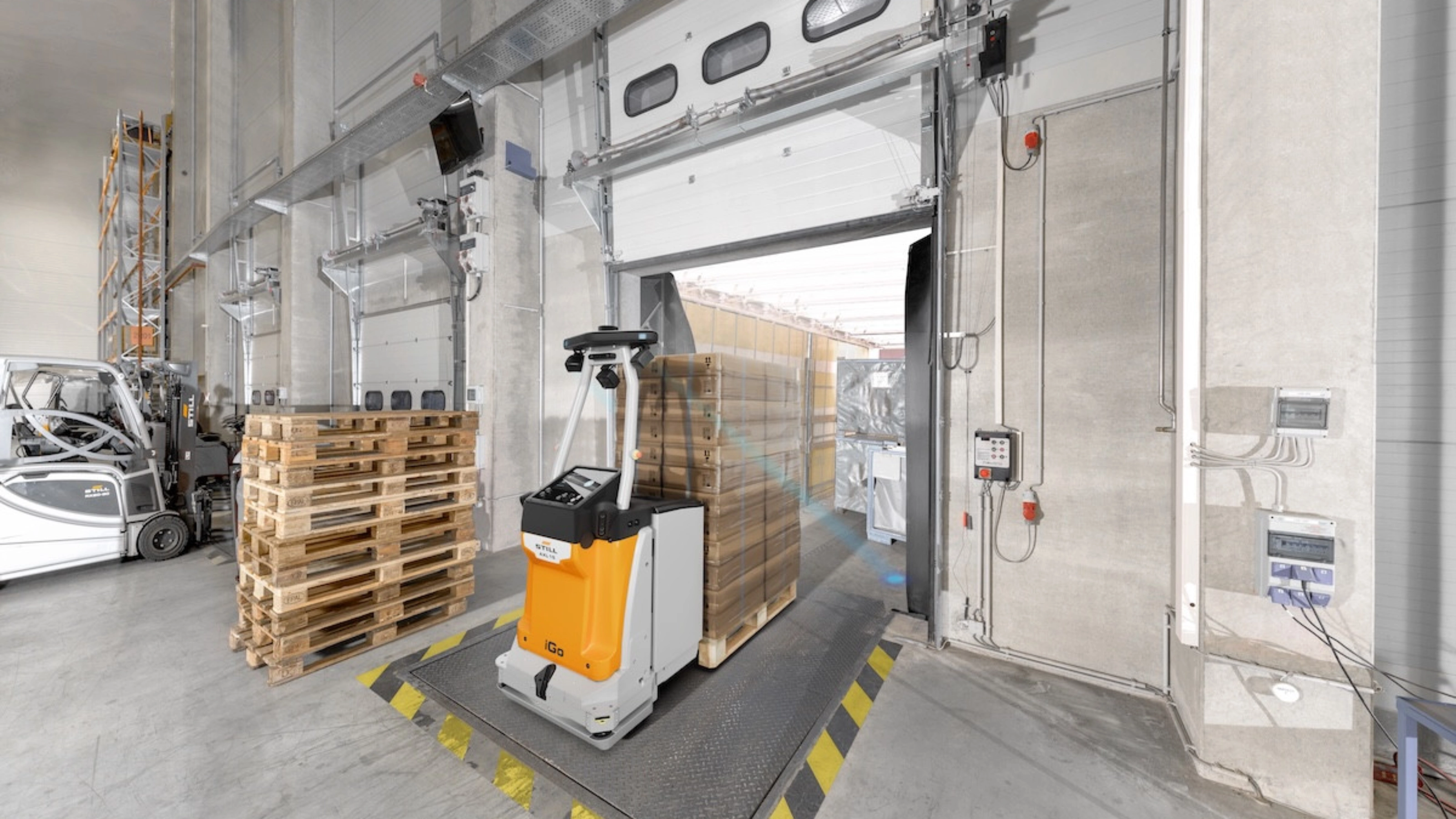 Autonomous mobile robot transporting goods at an industrial loading gate.