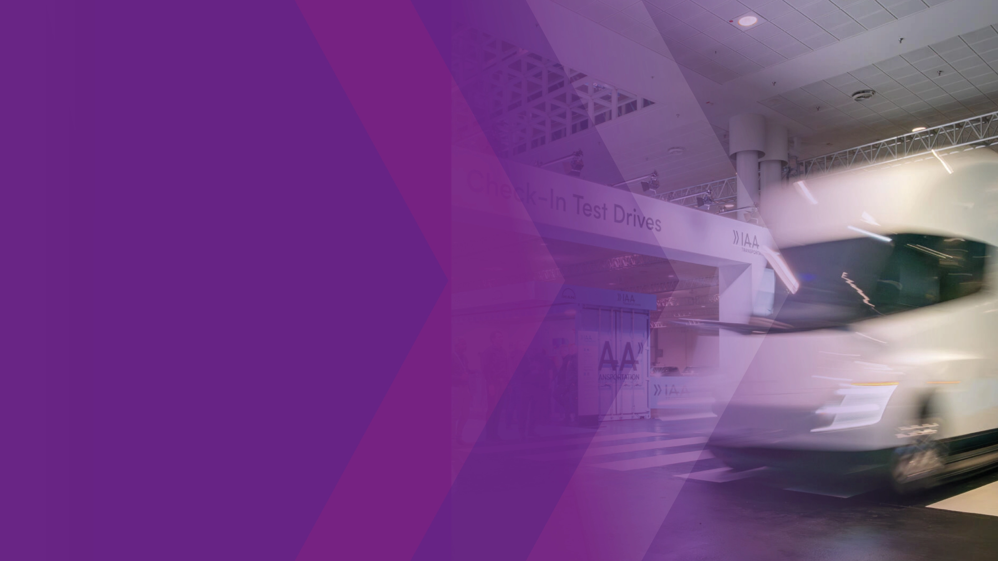 Blurred white truck at the IAA test drive area with a purple graphic overlay.
