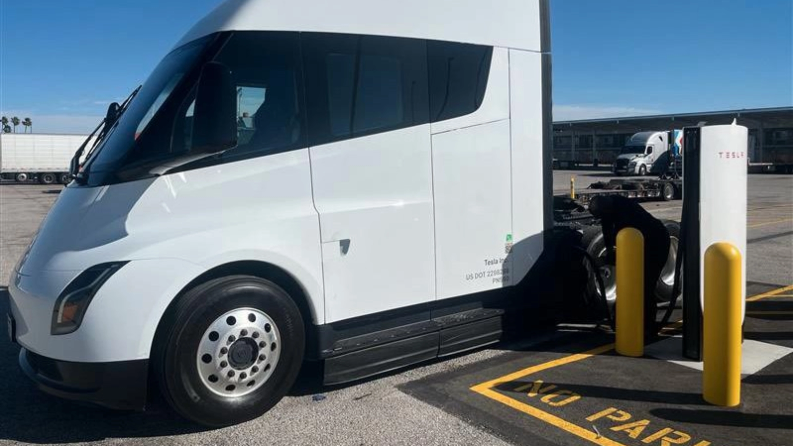 White Tesla Semi charging at a Tesla charging station.