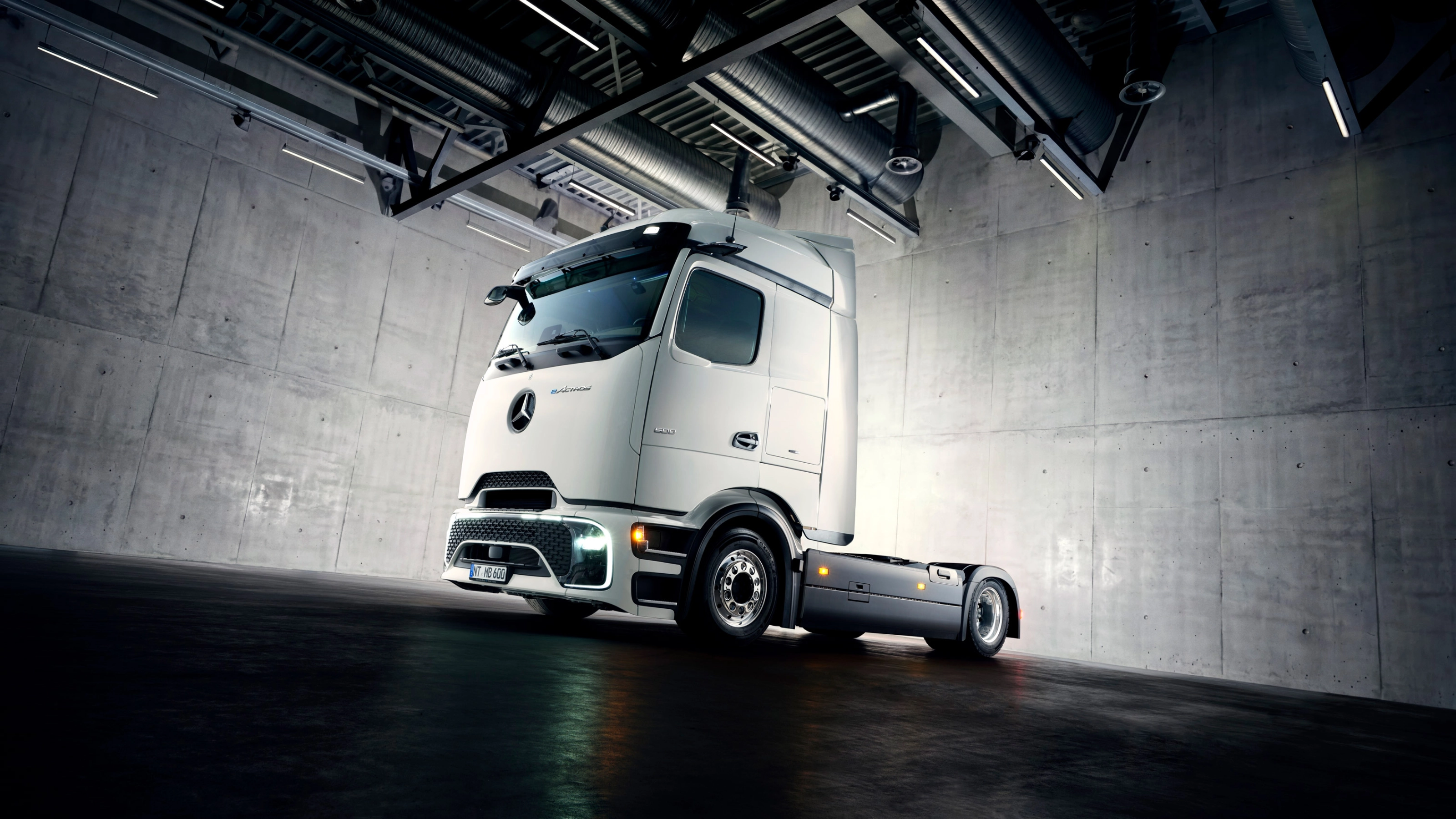 Autonomes Lkw-Fahrgestell in Industriehalle unter Scheinwerfern.