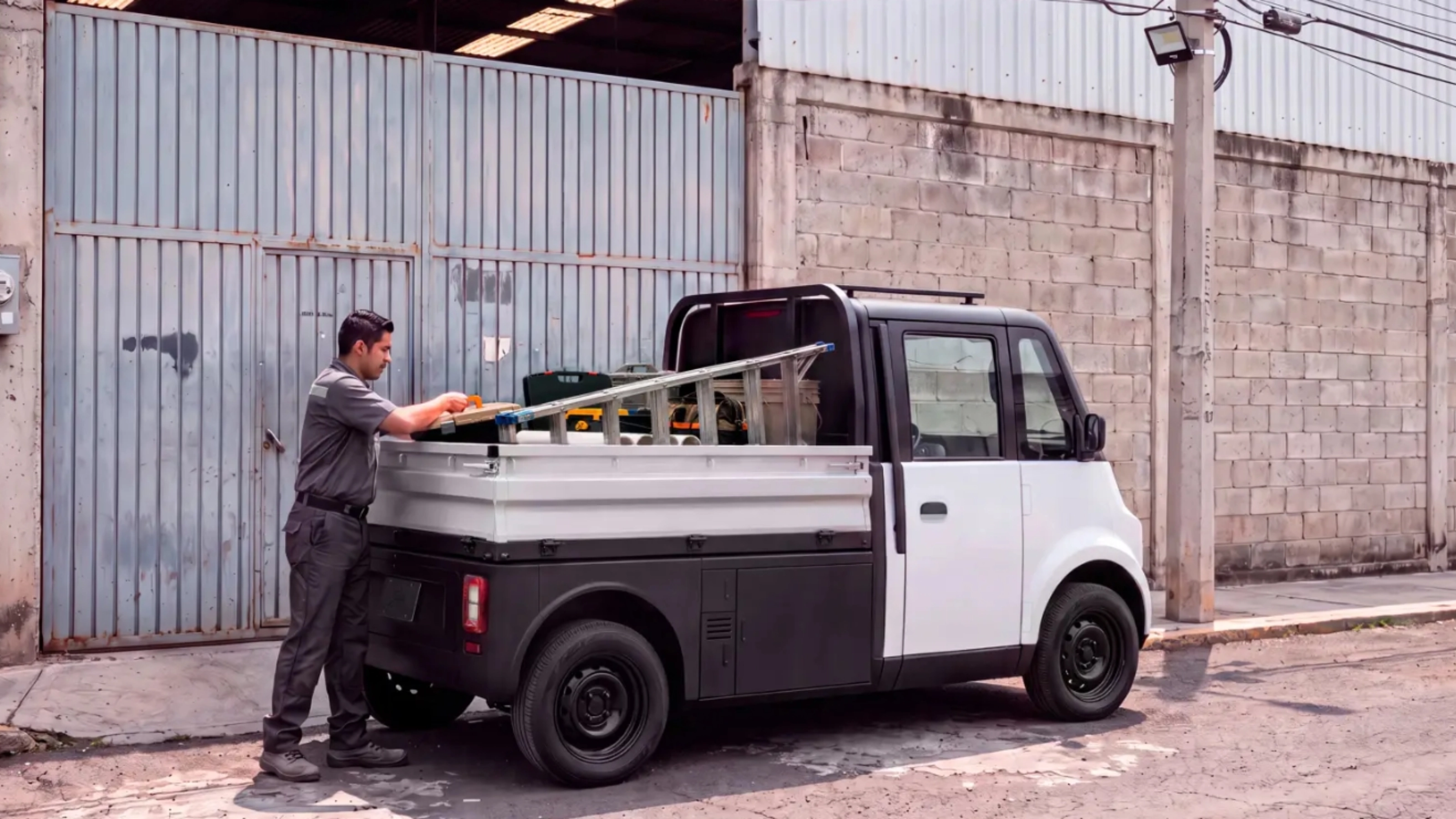 Compact Olinia utility vehicle being loaded at the roadside.