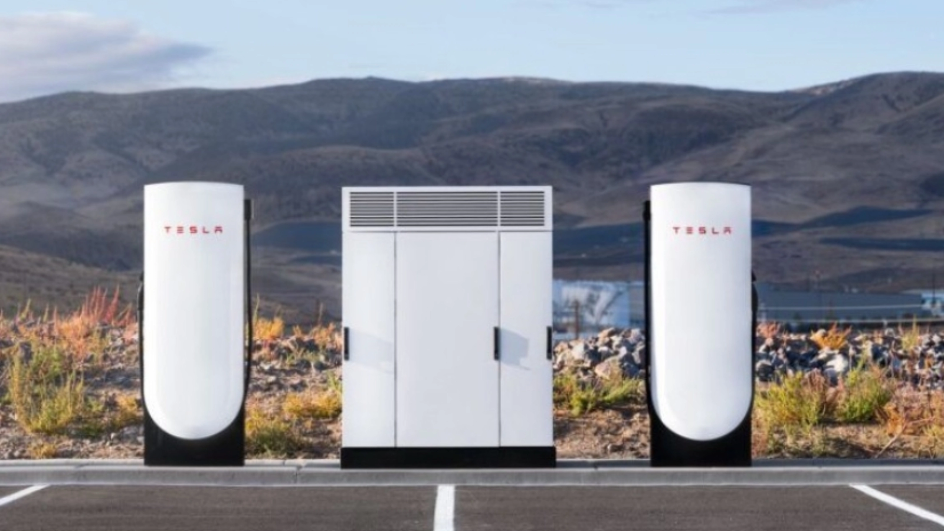 Tesla Supercharger station with two charging posts and a central power unit in a parking lot.