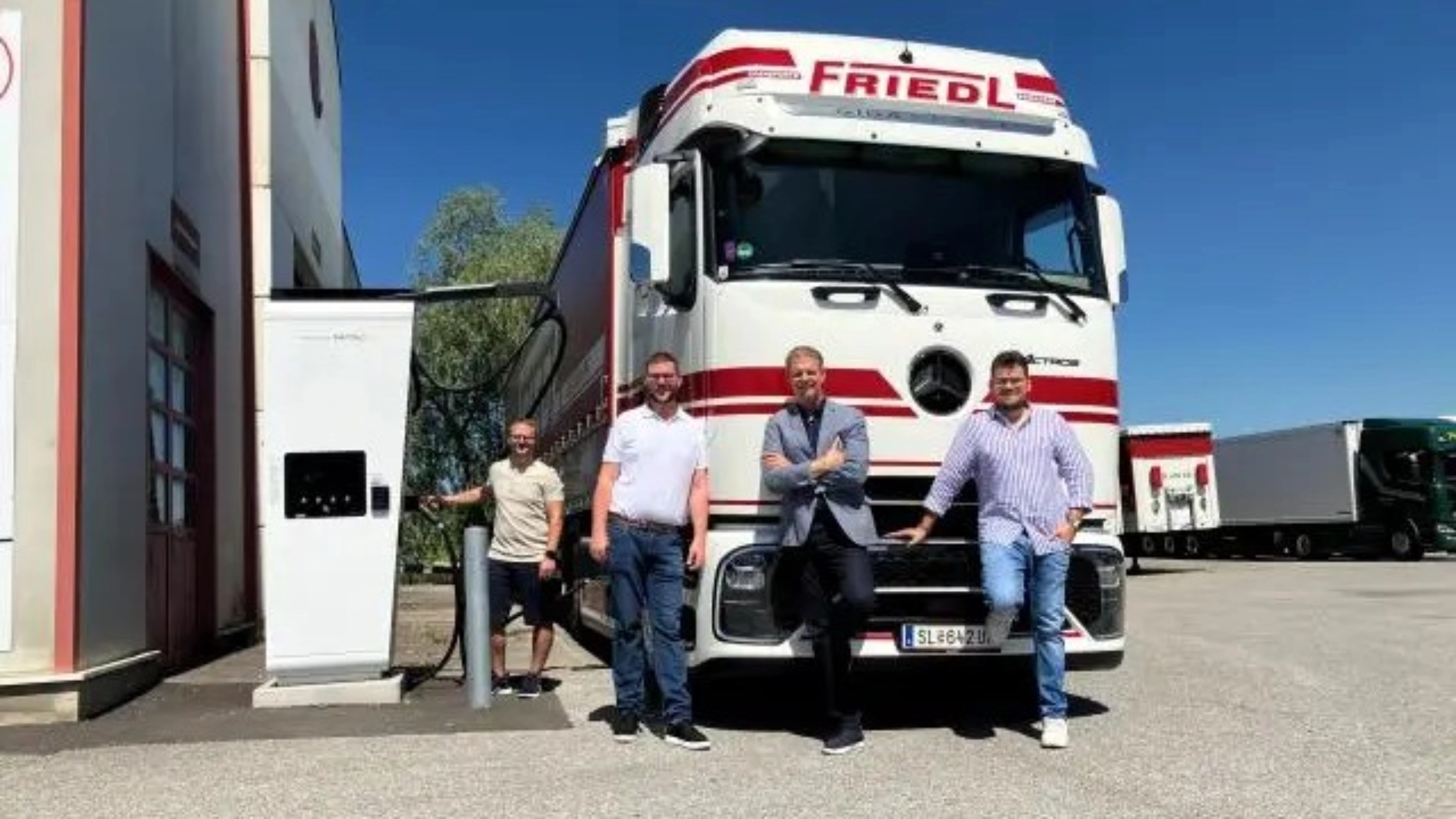 Vier Männer stehen vor einem weißen Frigel Lkw.