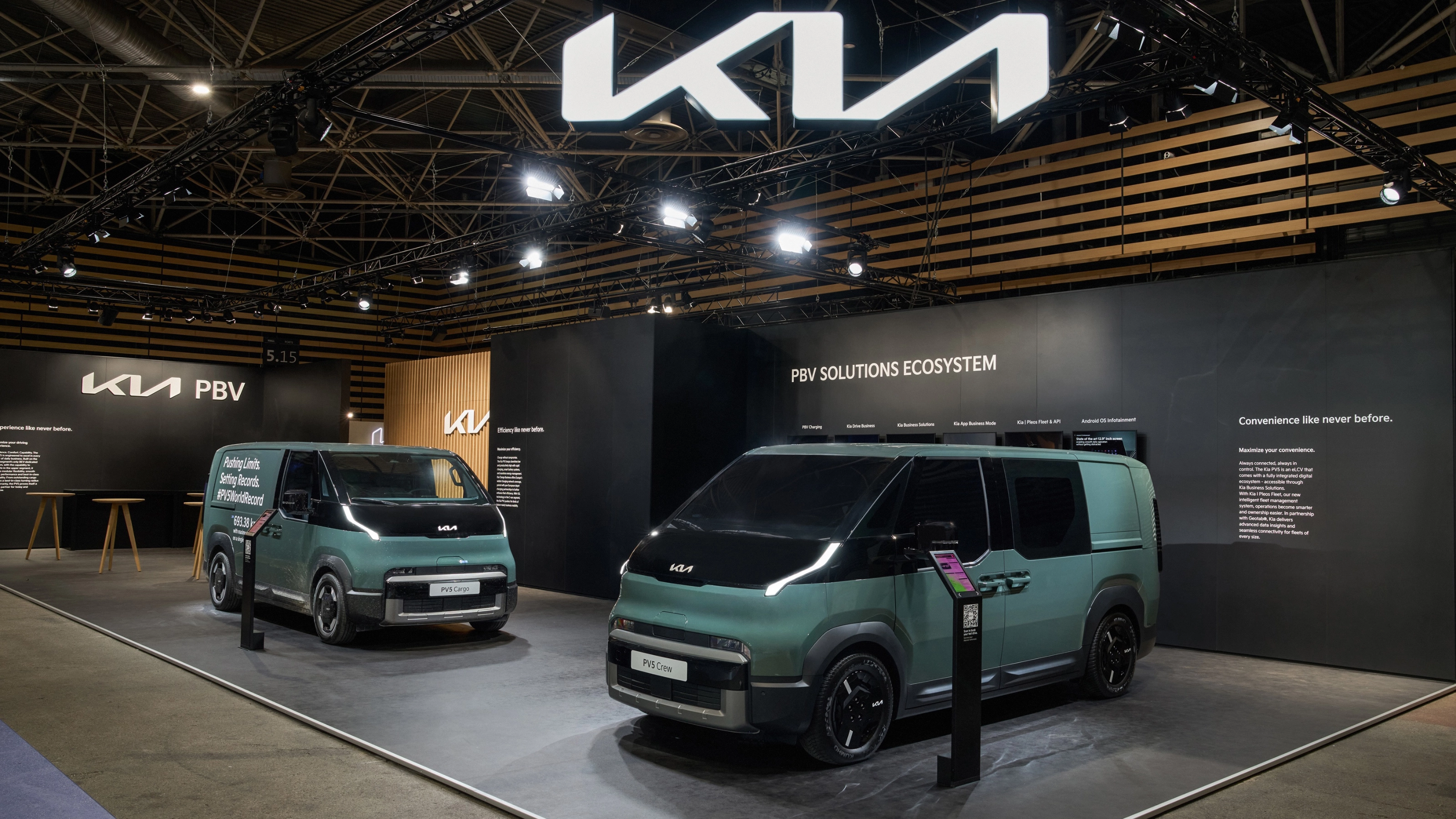Zwei grüne Kia PBV Transporter stehen auf einem Messestand mit Kia-Logo.