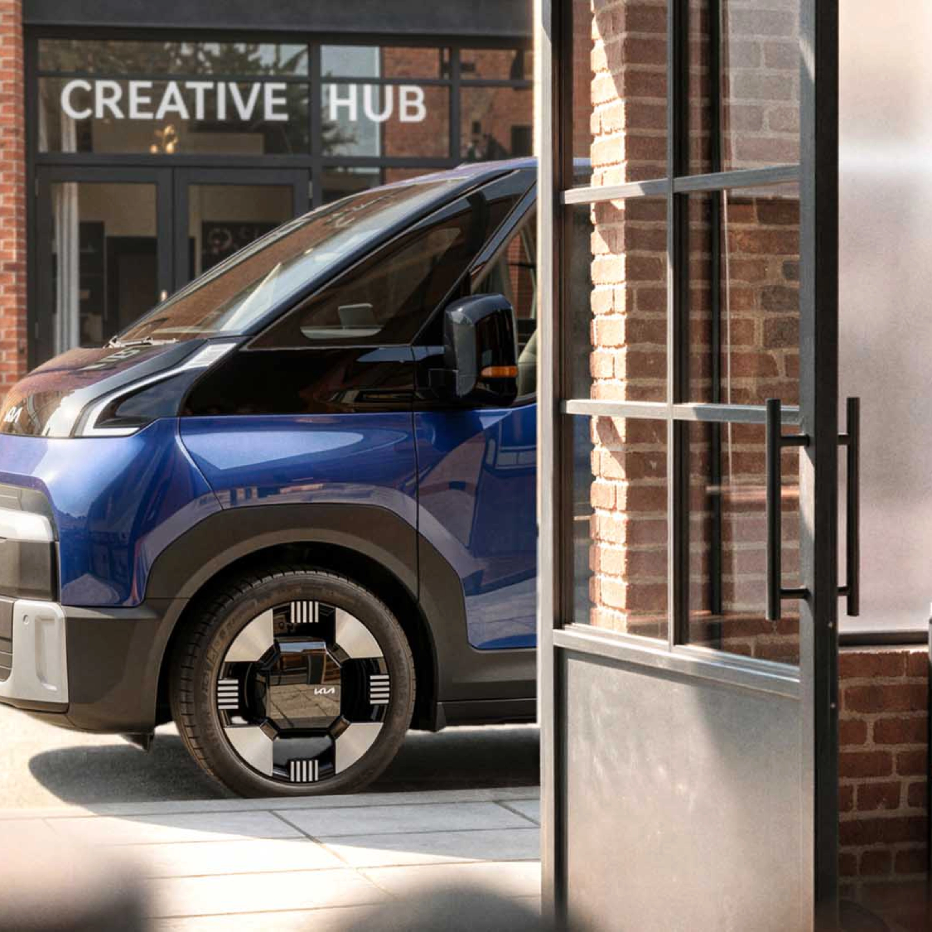 Blauer Kia PV7 vor einem Creative Hub.