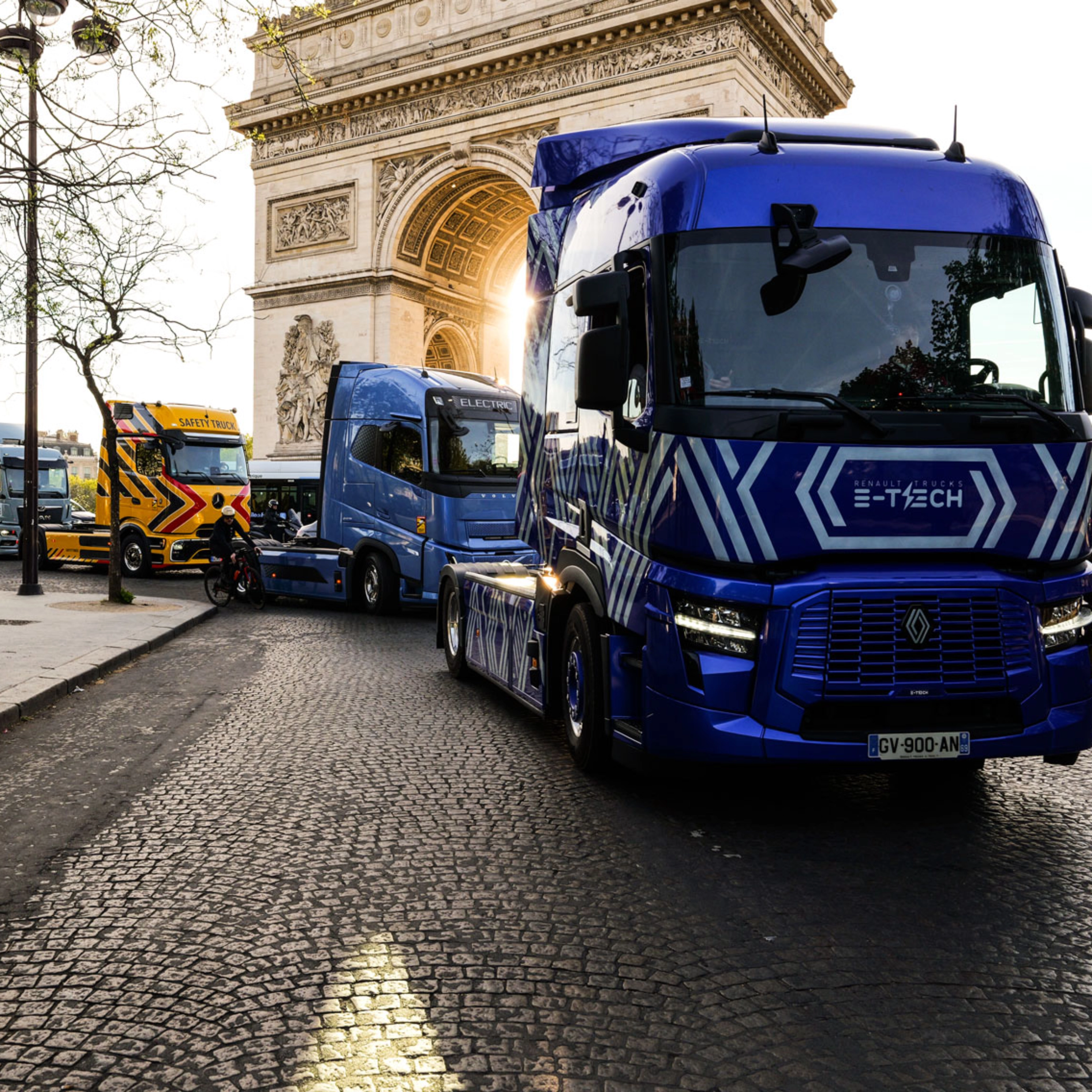 Blue electric truck driving past the Arc de Triomphe in Paris.