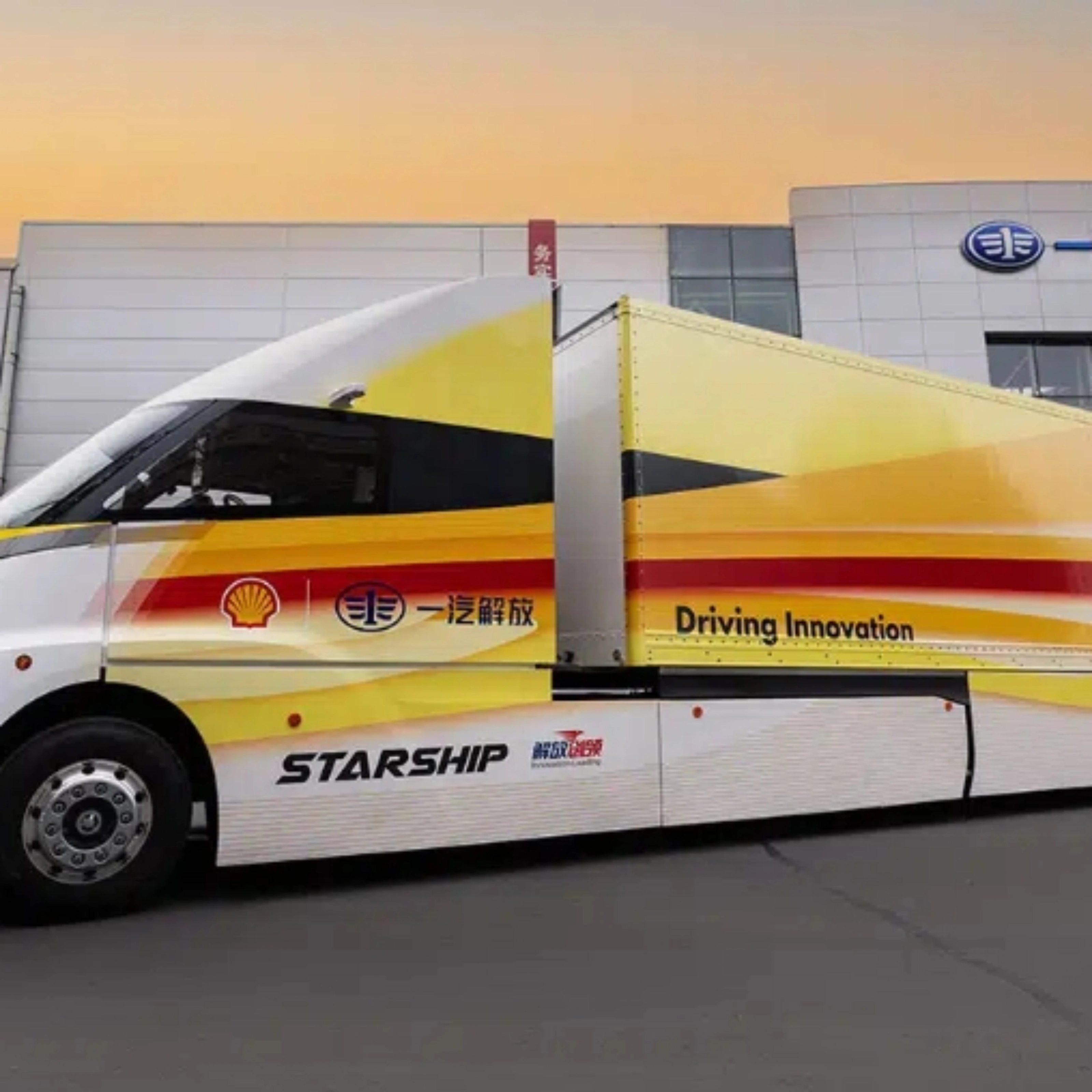 Weißer STARSHIP-Bus mit roten und gelben Streifen vor einem Industriegebäude bei Sonnenuntergang.