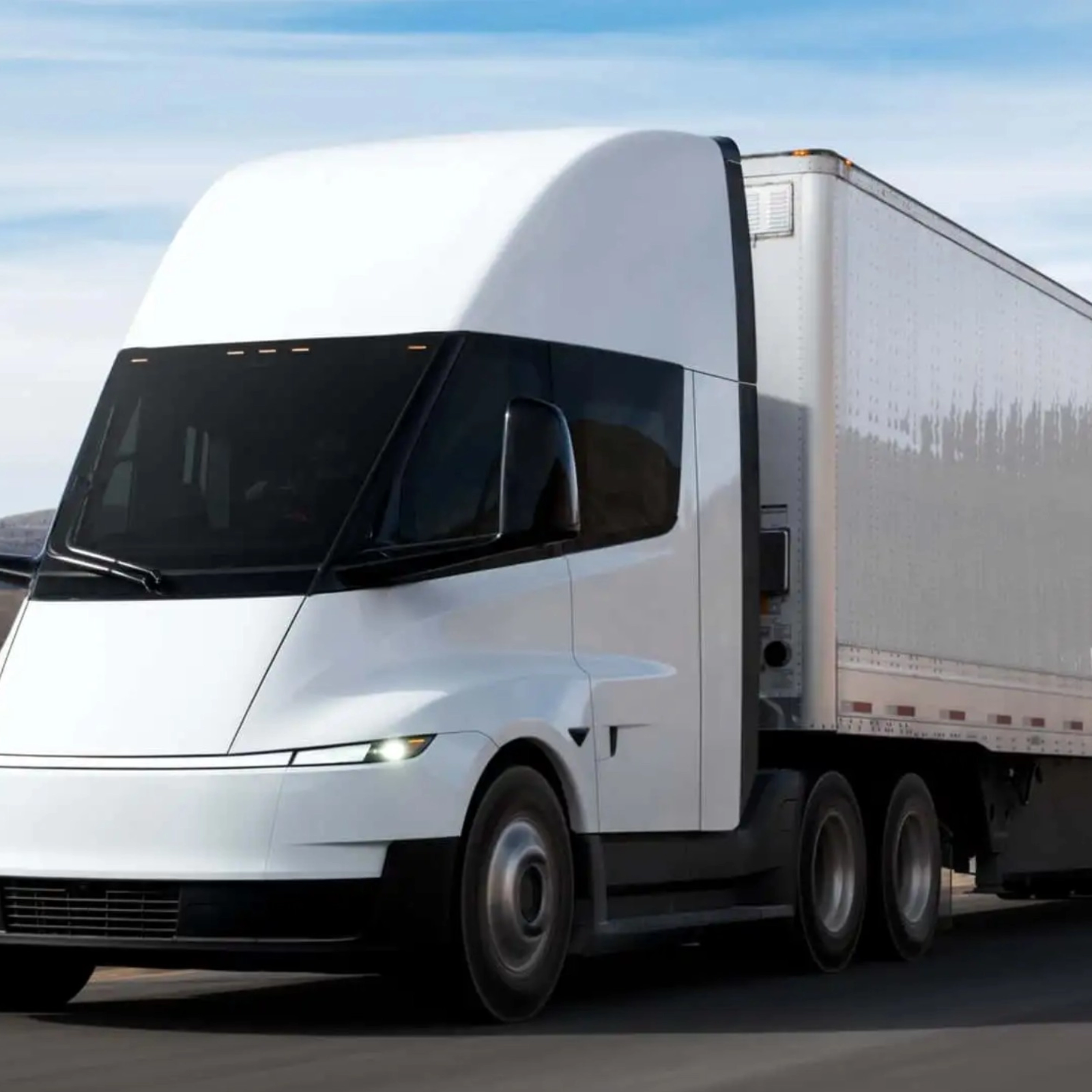 Electric semi-truck driving on a highway in a rural landscape.