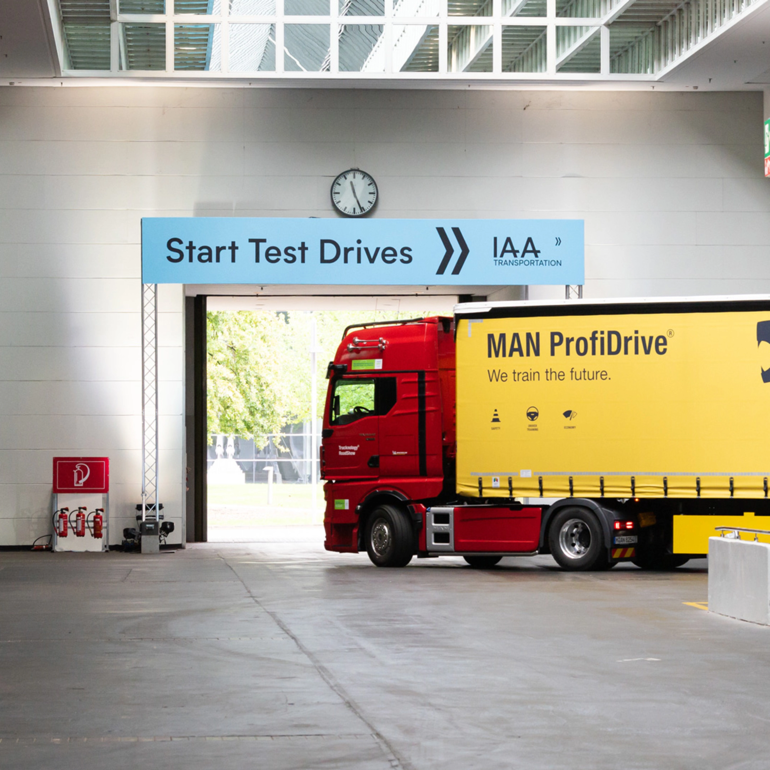 Truck with MAN ProfiDrive branding entering the IAA test‑drive start area inside a hall.