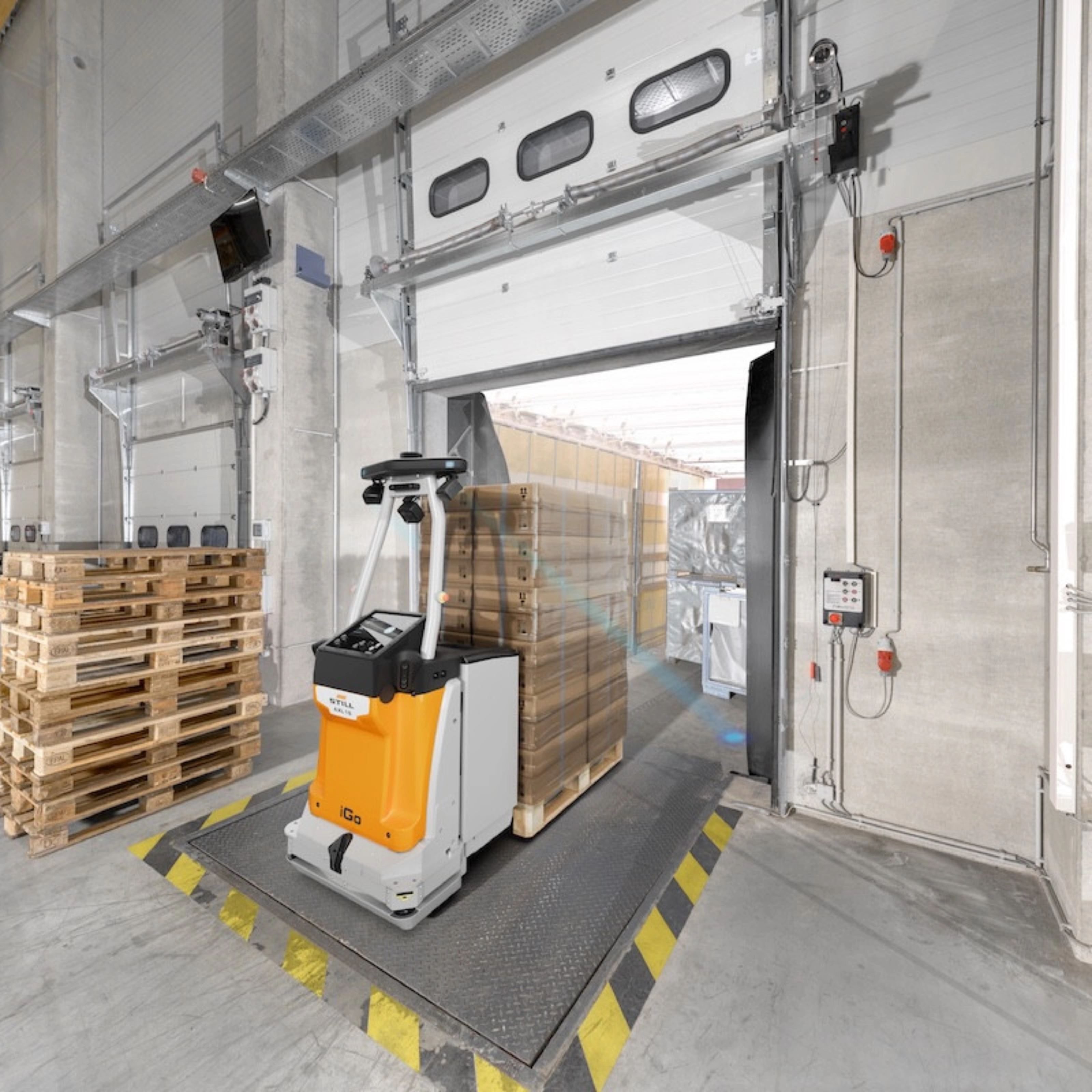 Autonomous mobile robot transporting goods at an industrial loading gate.