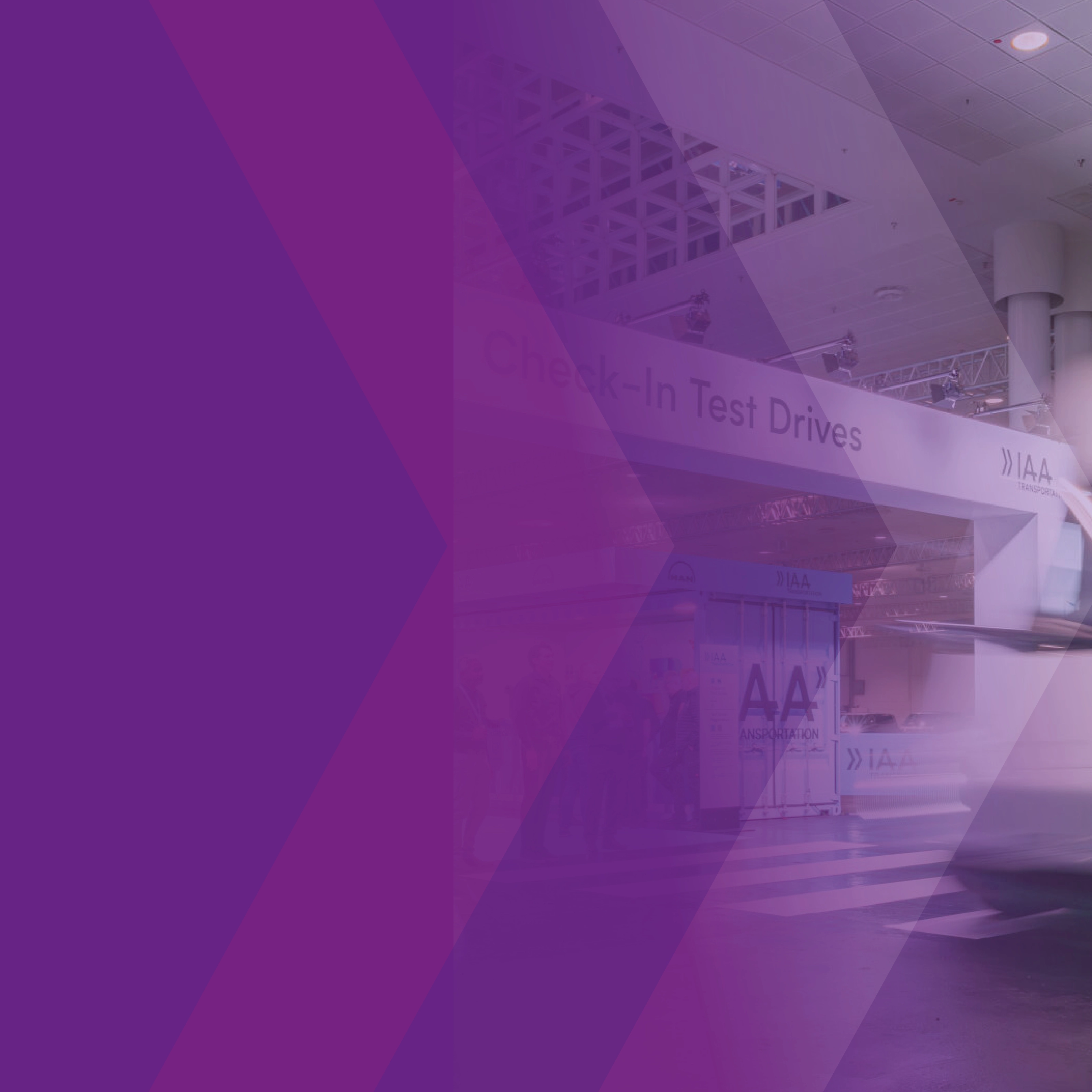 Blurred white truck at the IAA test drive area with a purple graphic overlay.