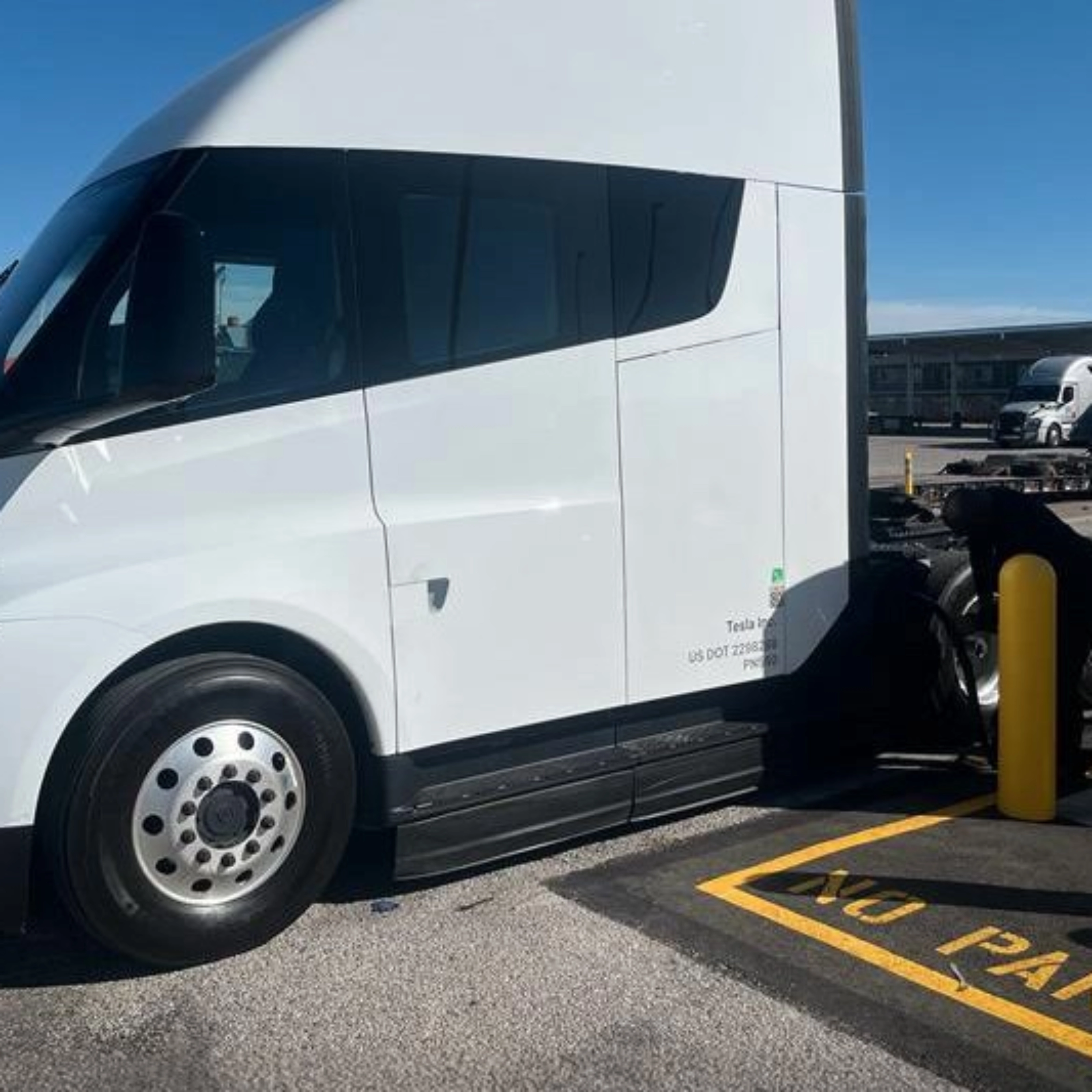 White Tesla Semi charging at a Tesla charging station.