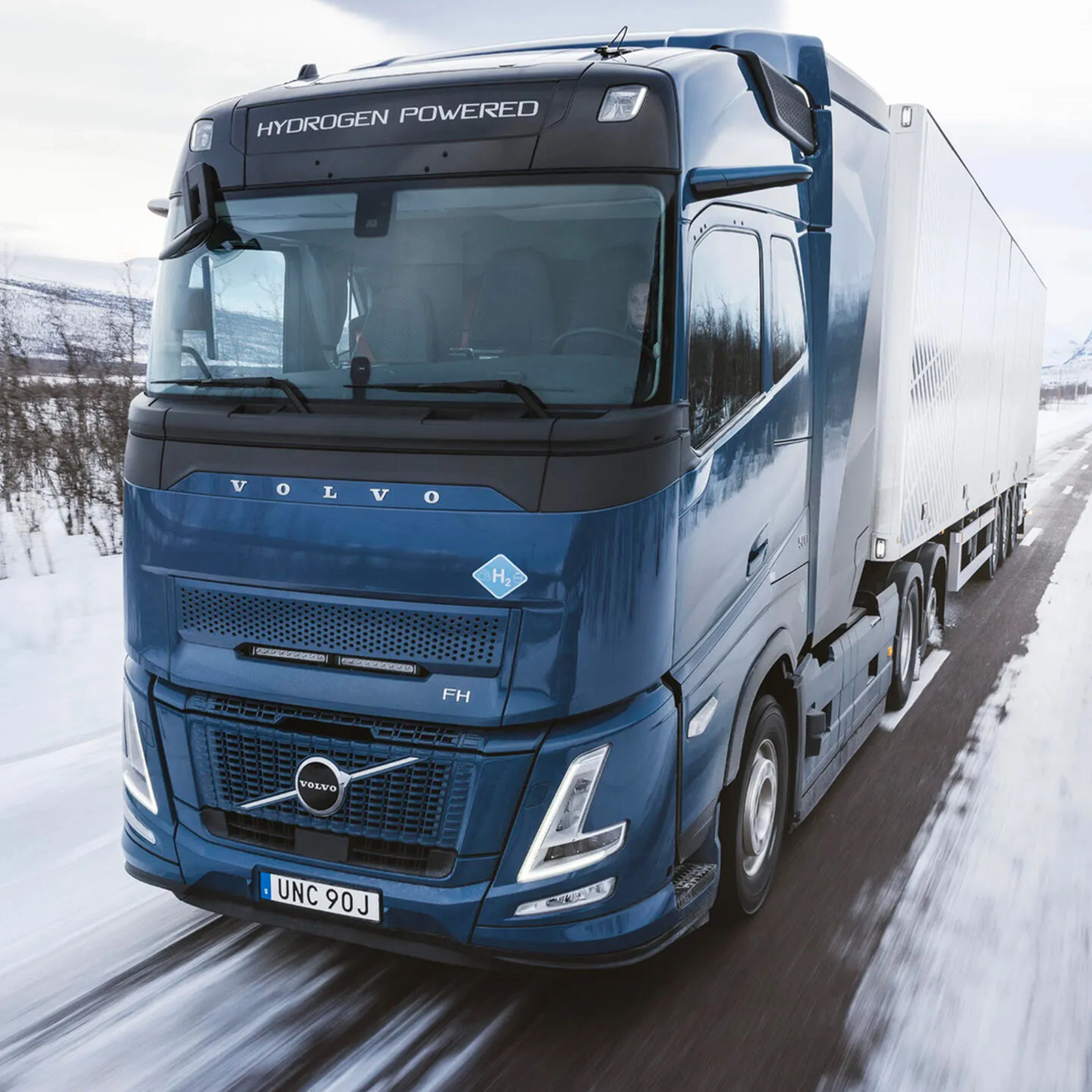Wasserstoffbetriebener Volvo-Lkw fährt auf verschneiter Straße durch Winterlandschaft.