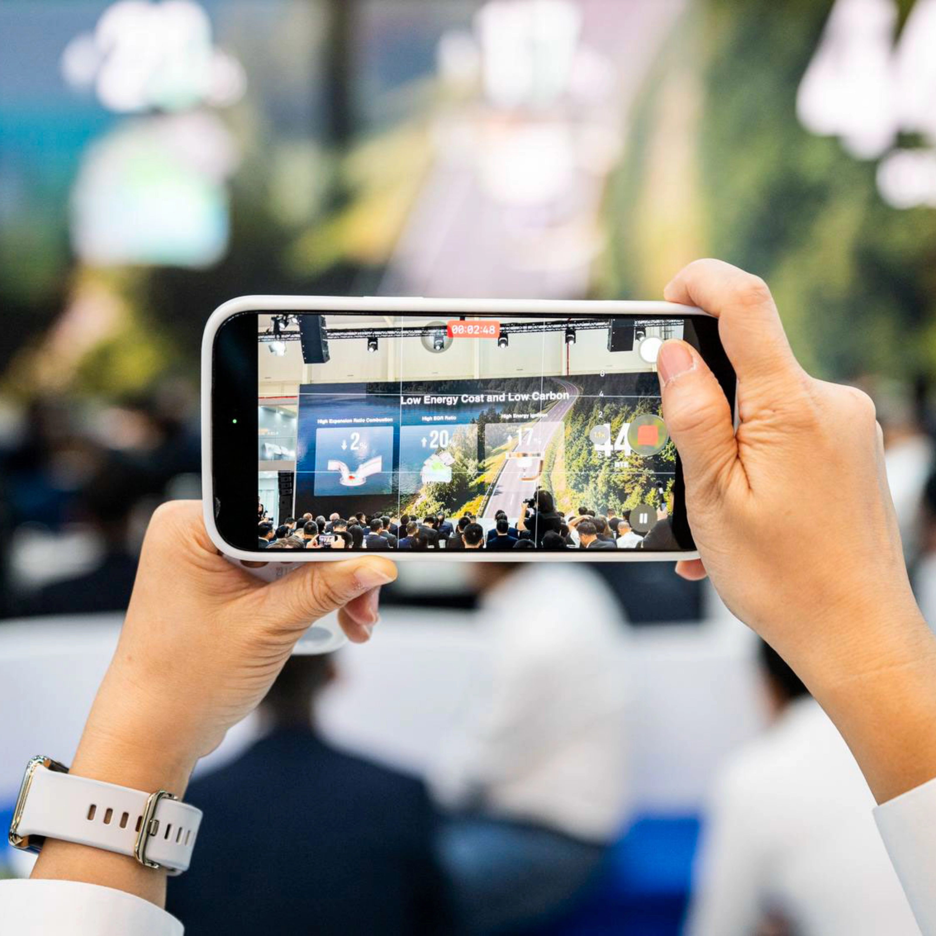 Person taking a photo of an event with a smartphone.