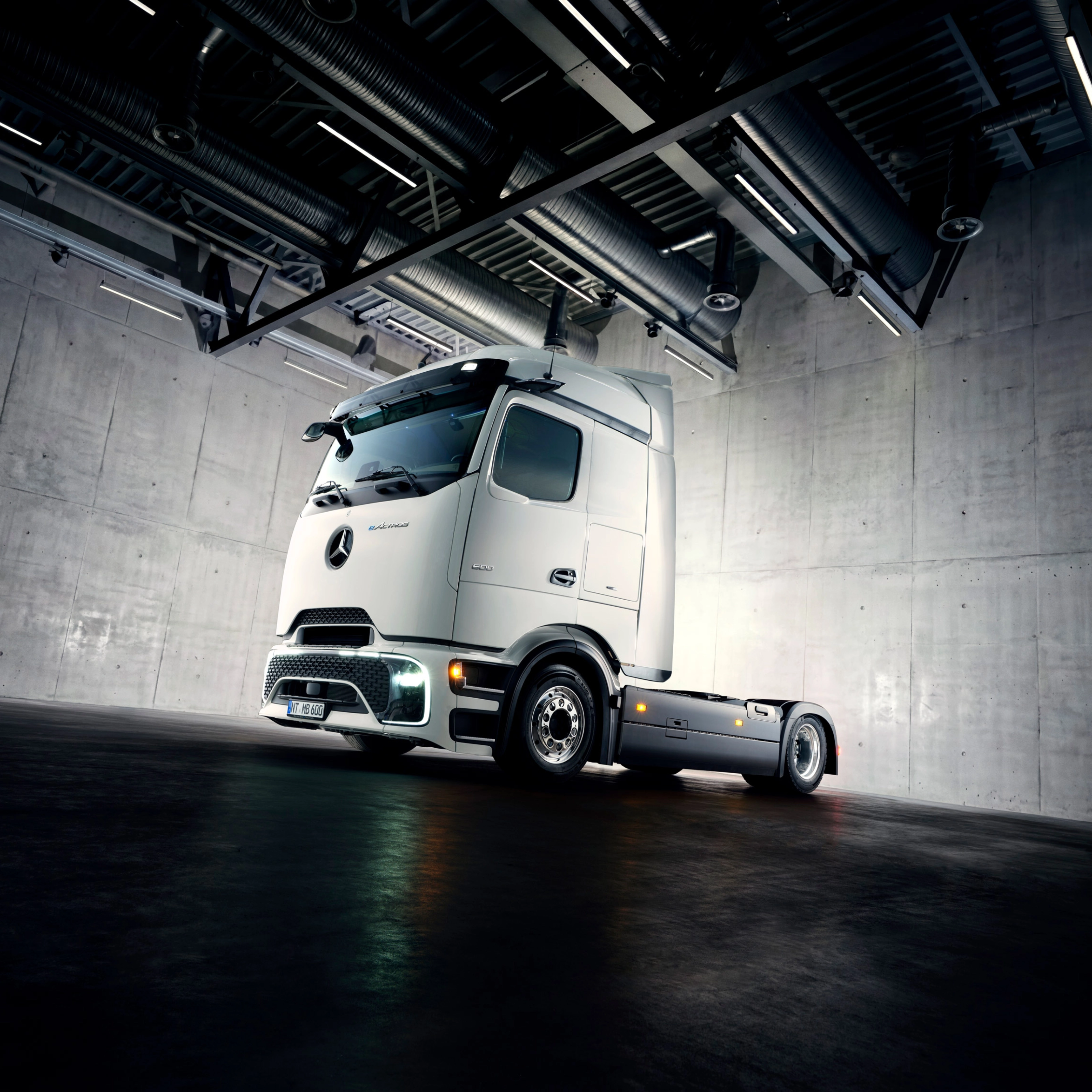 Autonomes Lkw-Fahrgestell in Industriehalle unter Scheinwerfern.