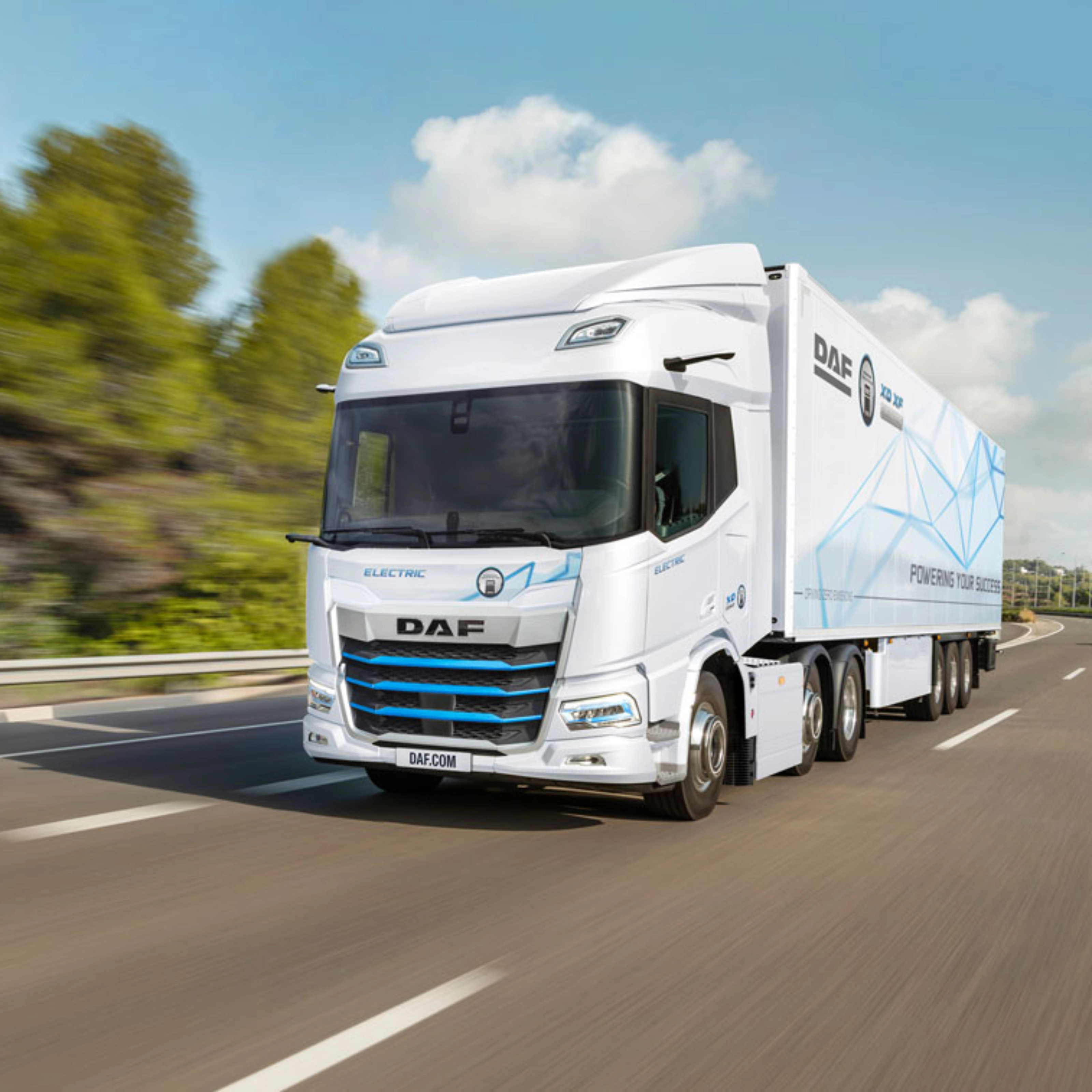 A white DAF electric truck is driving on a curved highway surrounded by greenery.