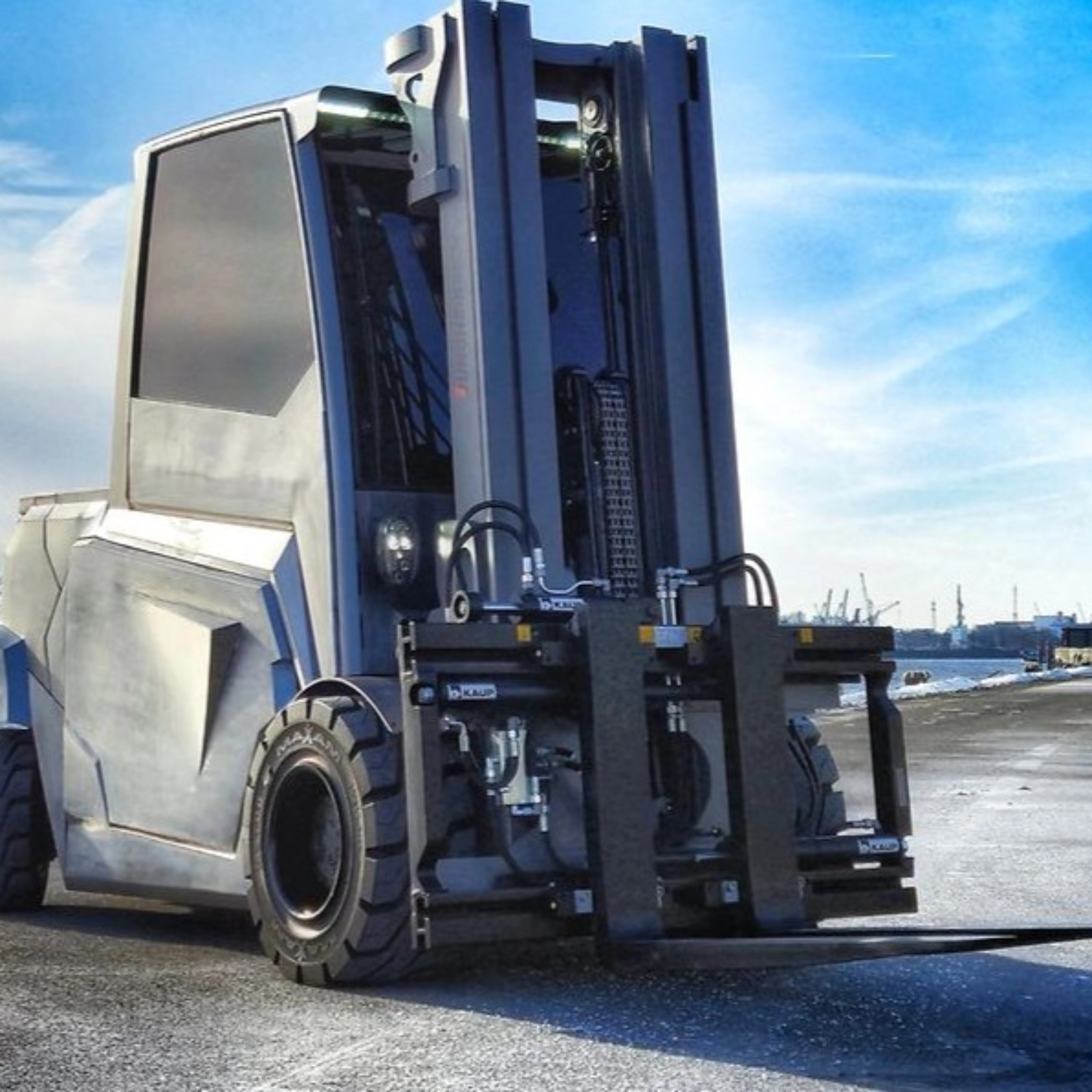 Large industrial forklift parked at a harbor loading area.