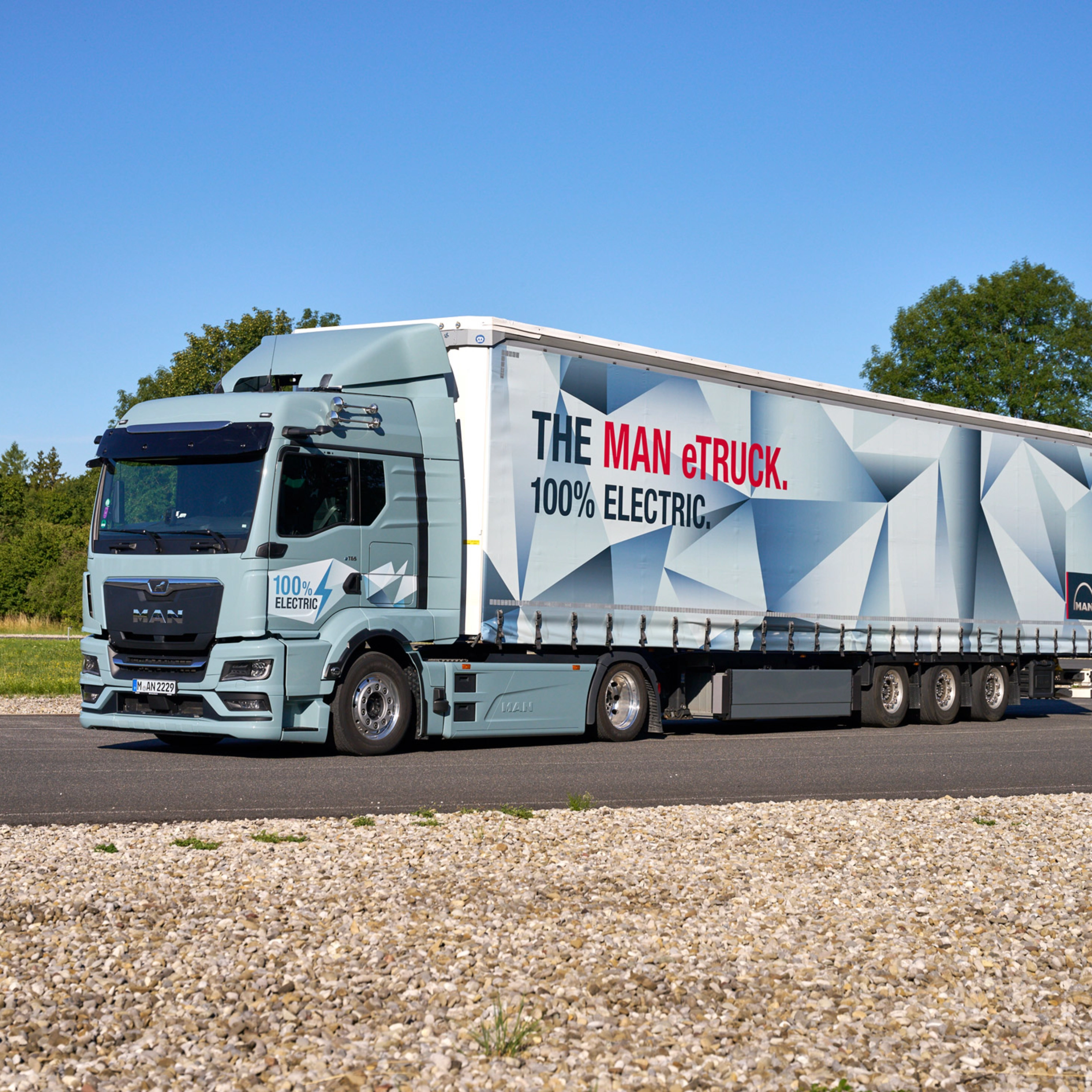 MAN truck with a trailer featuring a large graphic parked on a paved area.
