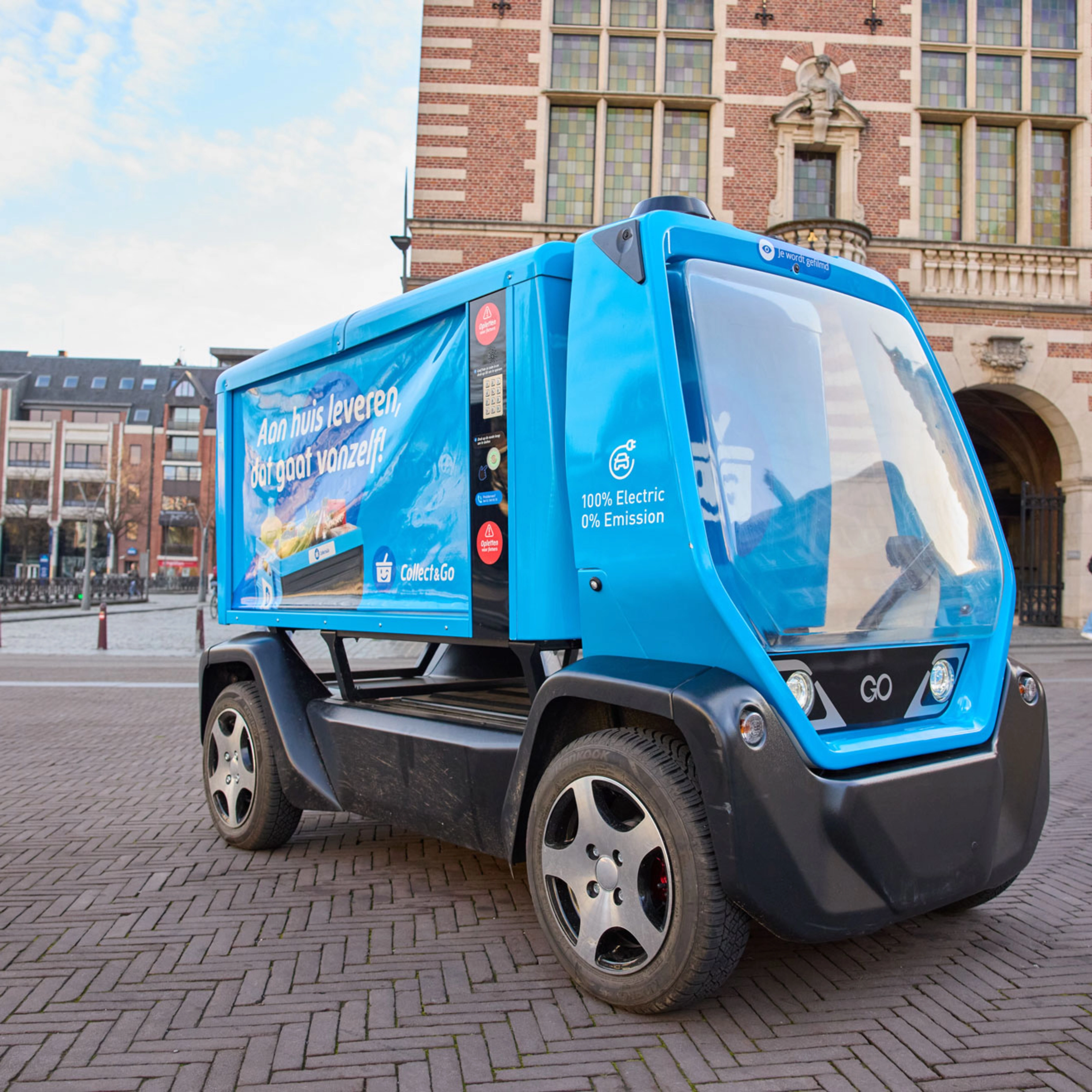 Kleines blaues Elektro-Müllfahrzeug auf einem Stadtplatz.